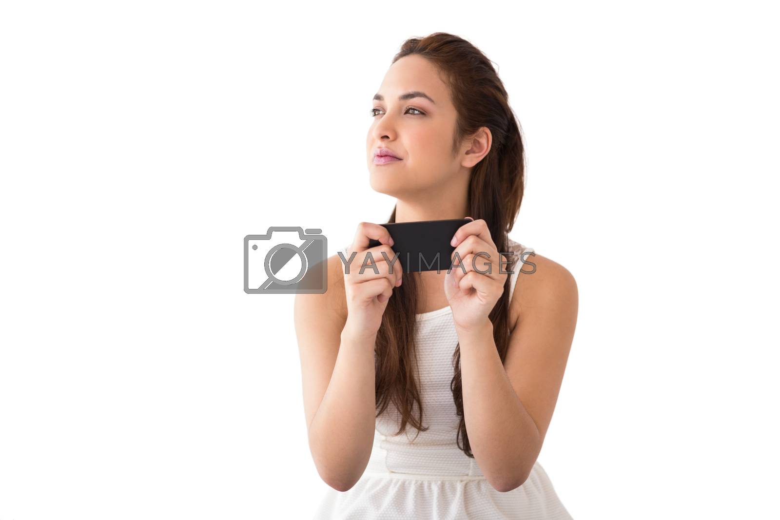 Royalty free image of Thoughtful brunette holding her phone  by Wavebreakmedia