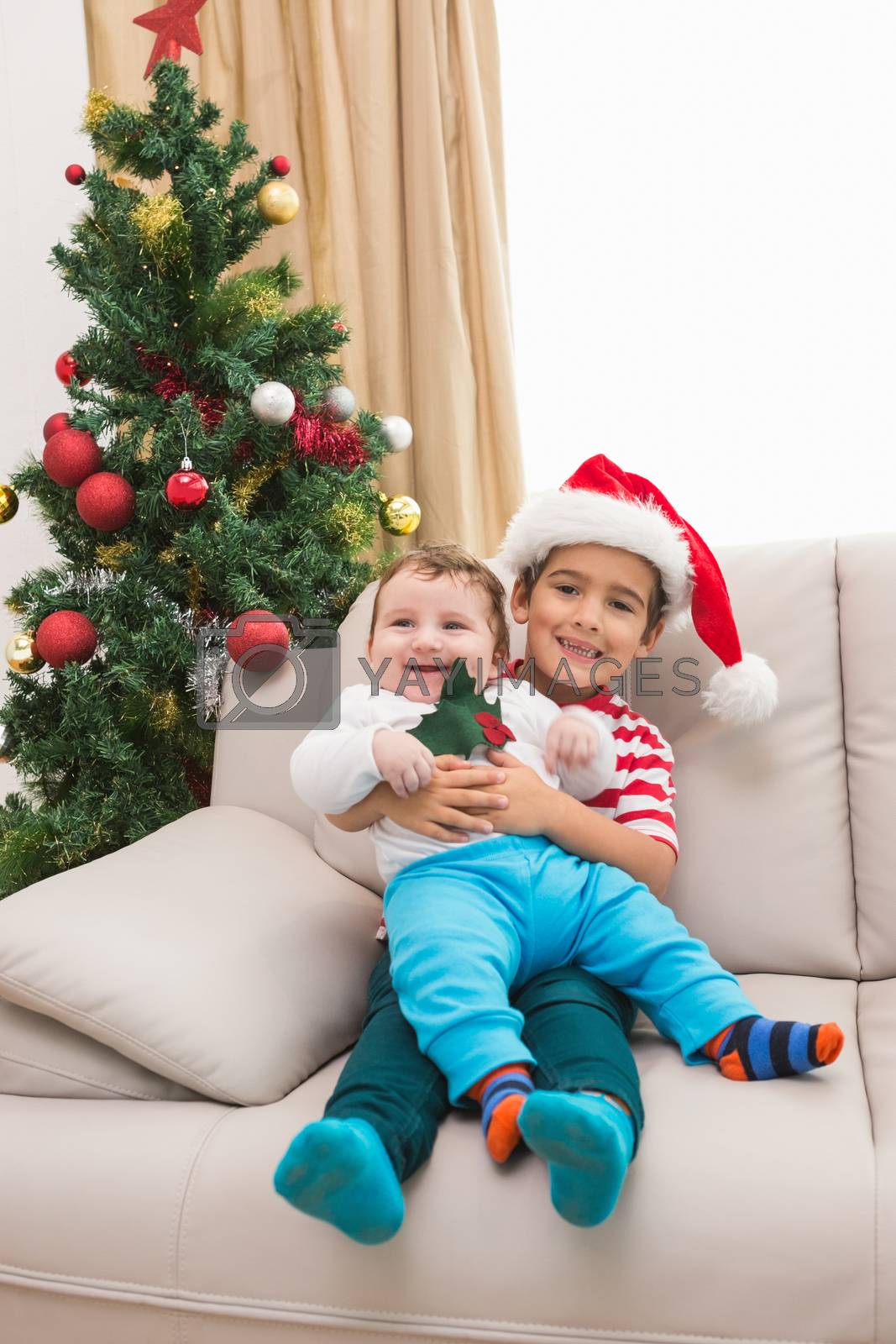 Royalty free image of Cute boy and baby brother on couch at christmas by Wavebreakmedia