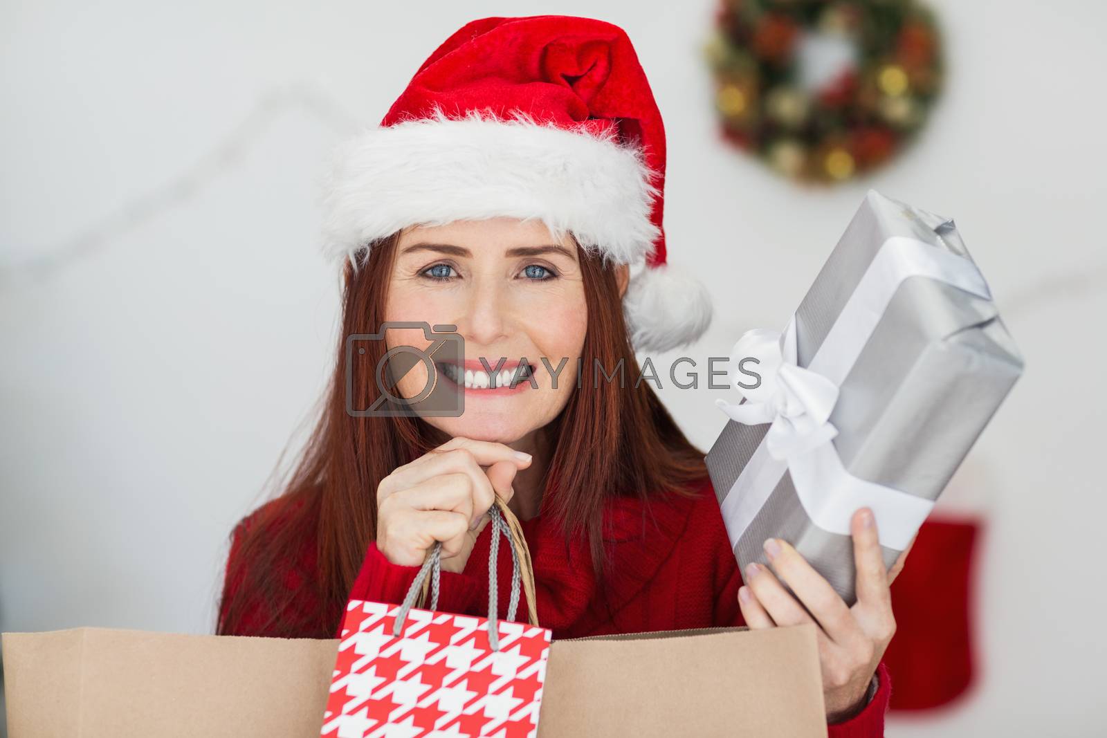 Royalty free image of Festive redhead holding christmas gifts by Wavebreakmedia