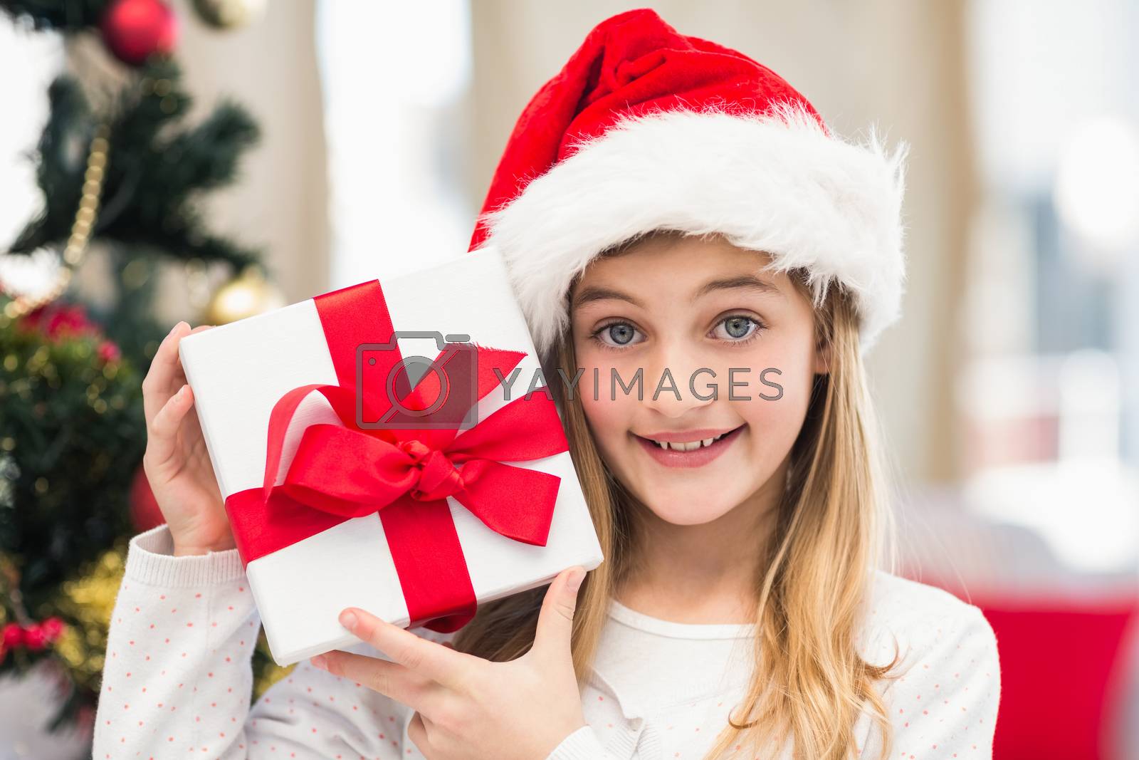 Royalty free image of Festive little girl holding a gift by Wavebreakmedia