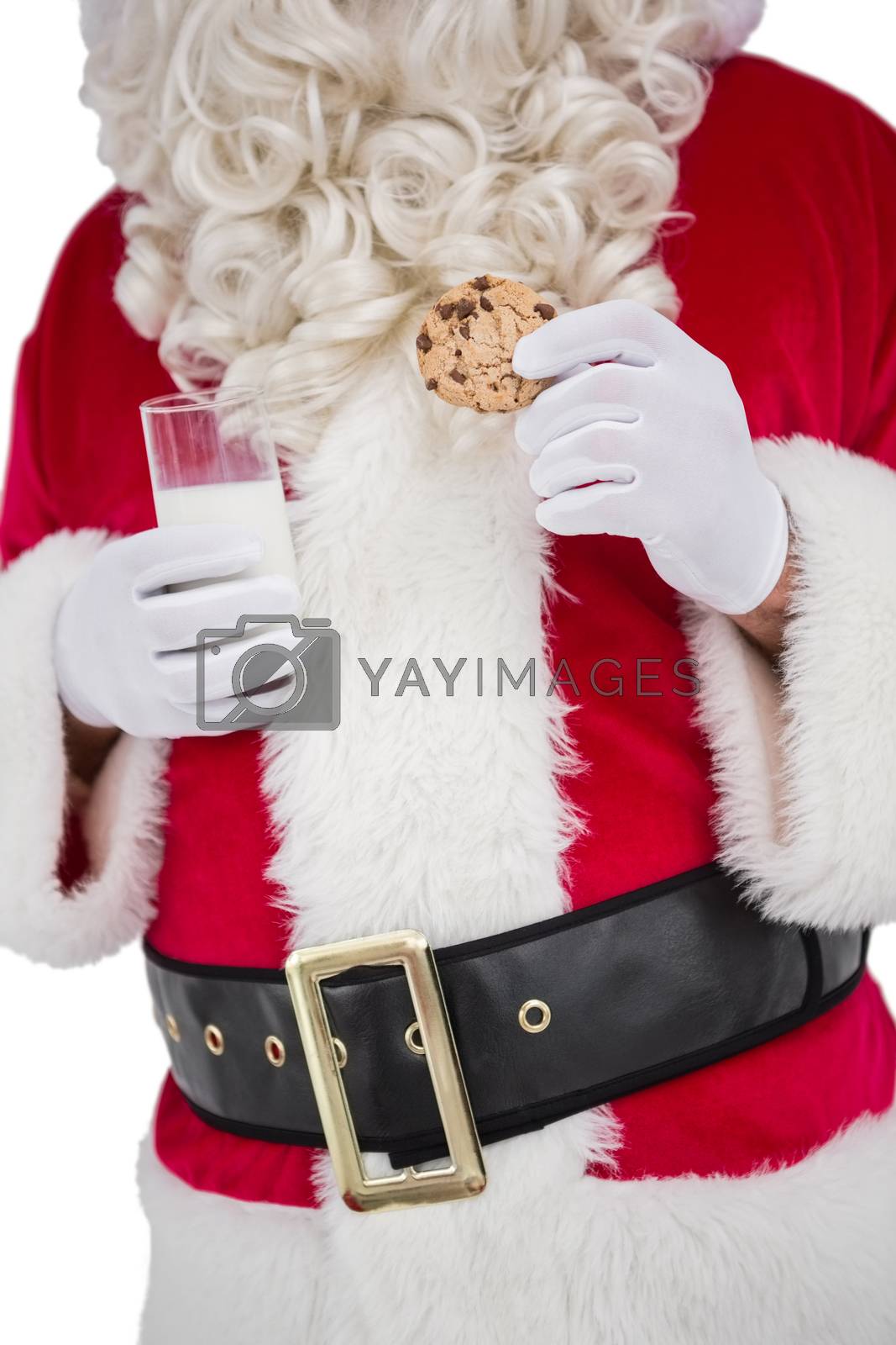 Royalty free image of Santa holding glass of milk and cookie by Wavebreakmedia