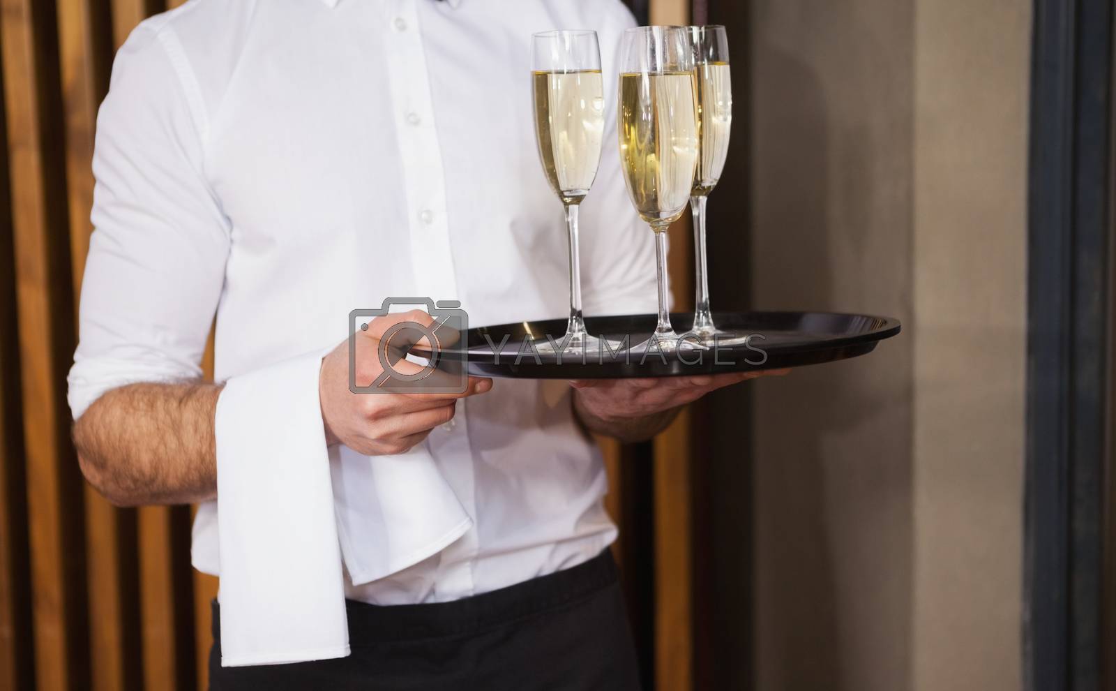 Royalty free image of Waiter holding tray of champagne by Wavebreakmedia