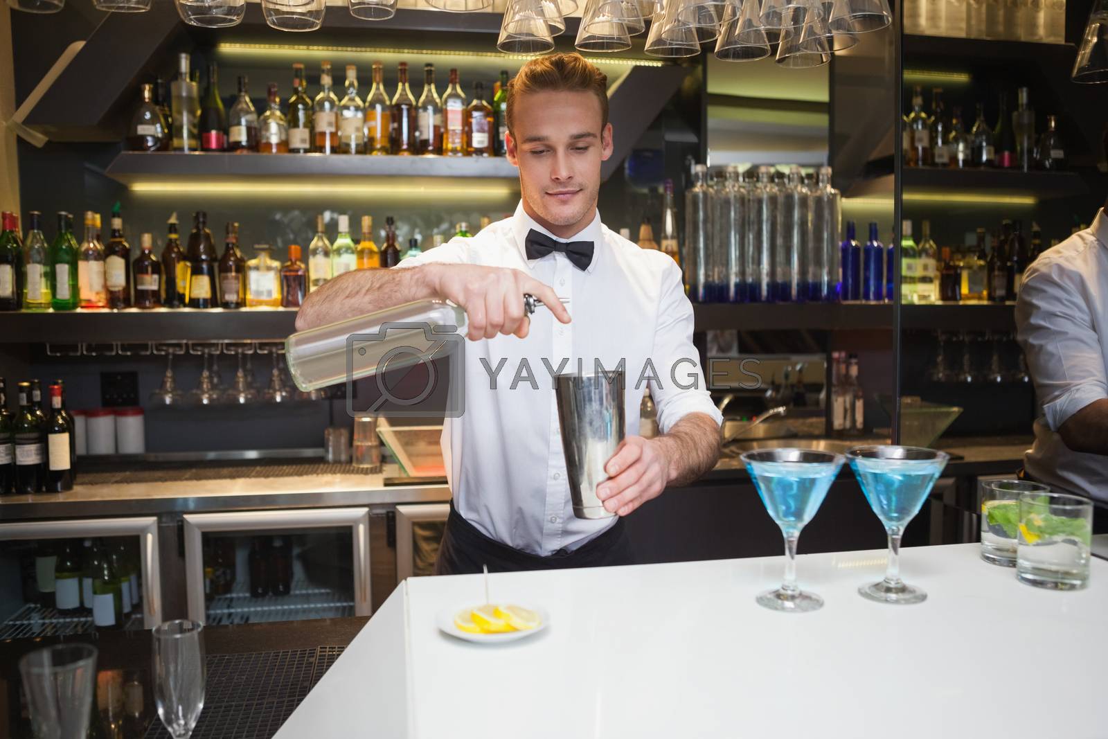 Royalty free image of Smiling bartender preparing a drink at bar counter by Wavebreakmedia