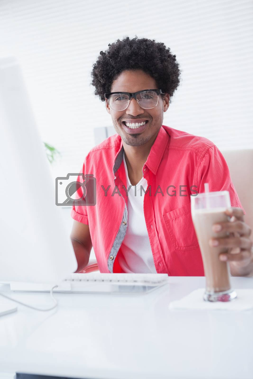 Royalty free image of Smiling casual businessman holding glass of milkshake by Wavebreakmedia