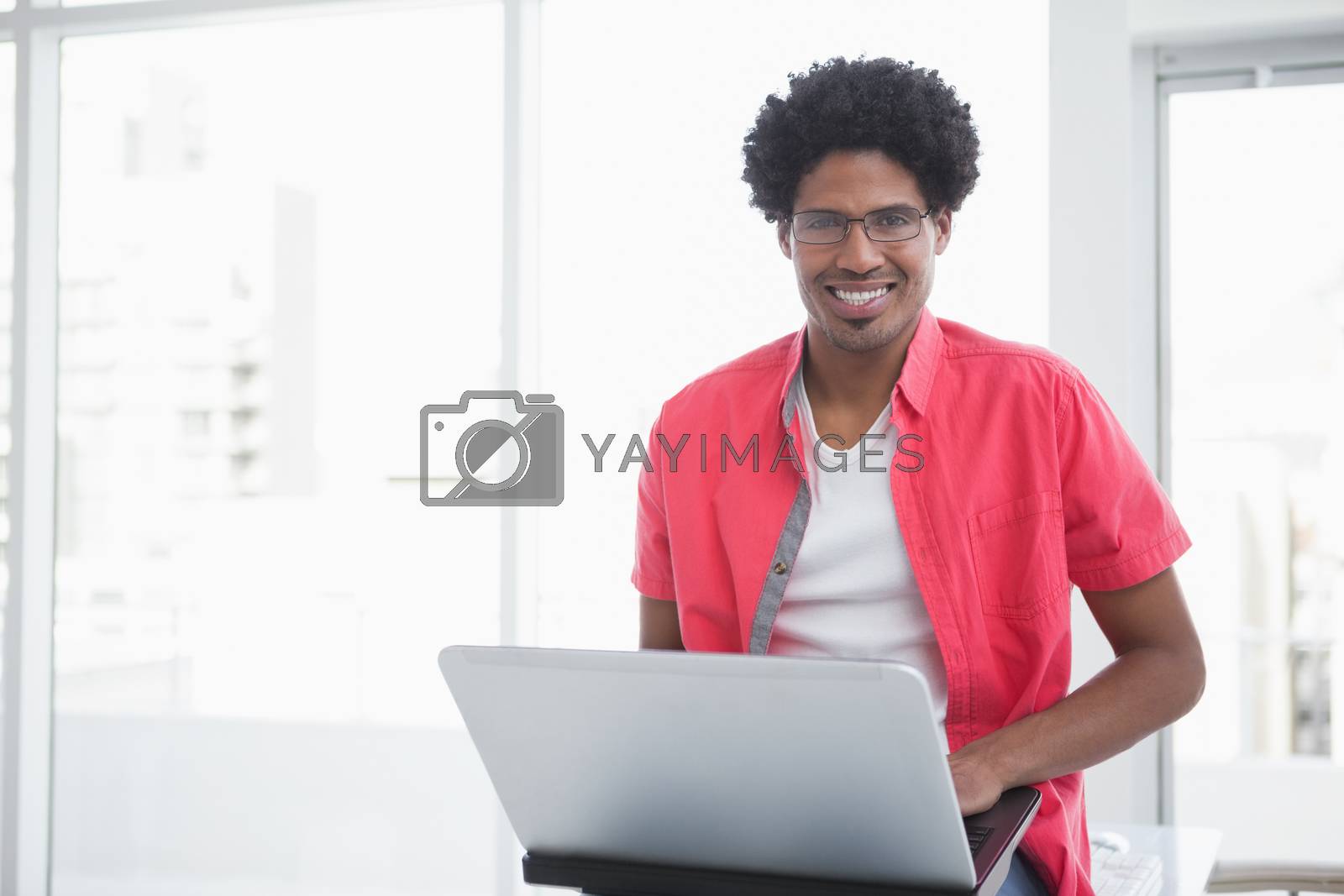 Royalty free image of Casual businessman smiling and using laptop by Wavebreakmedia