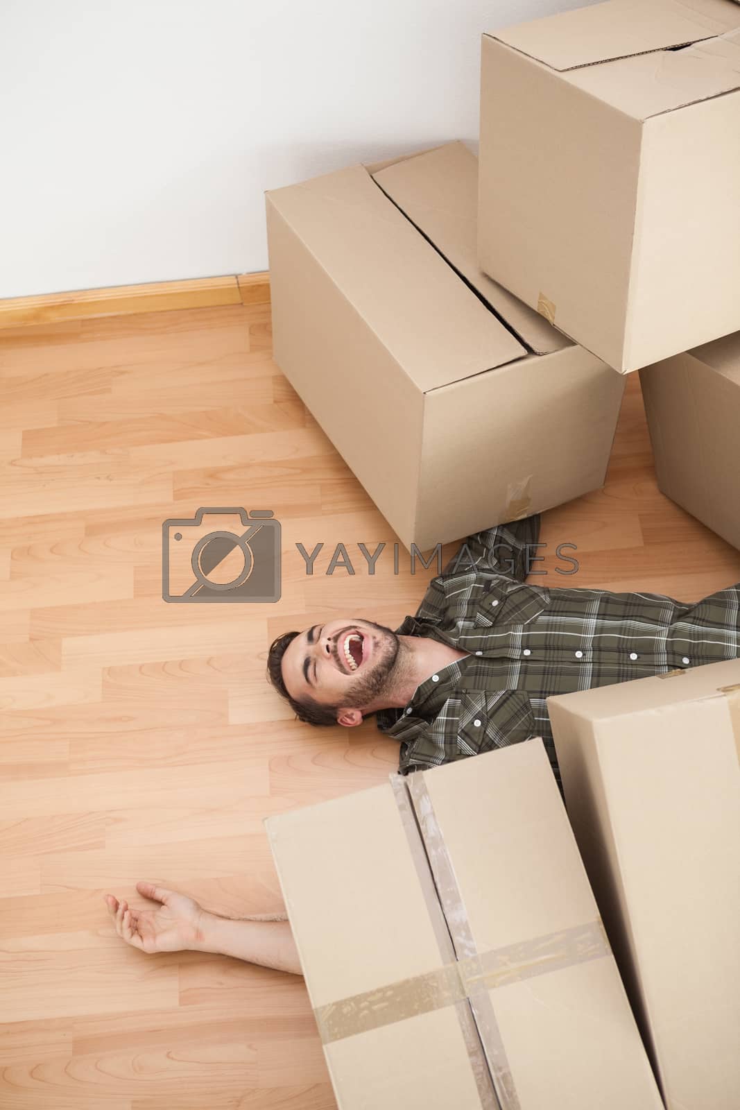 Royalty free image of Man lying under fallen boxes by Wavebreakmedia