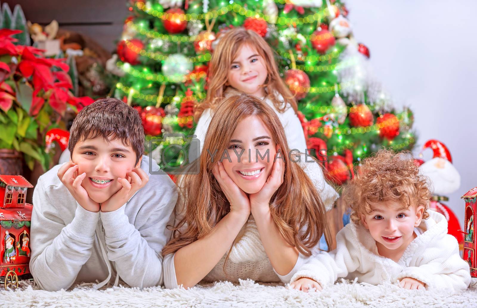 Happy Christmas celebration, cheerful family having fun at home, lying down near beautiful decorated Christmas tree, love and happiness concept
