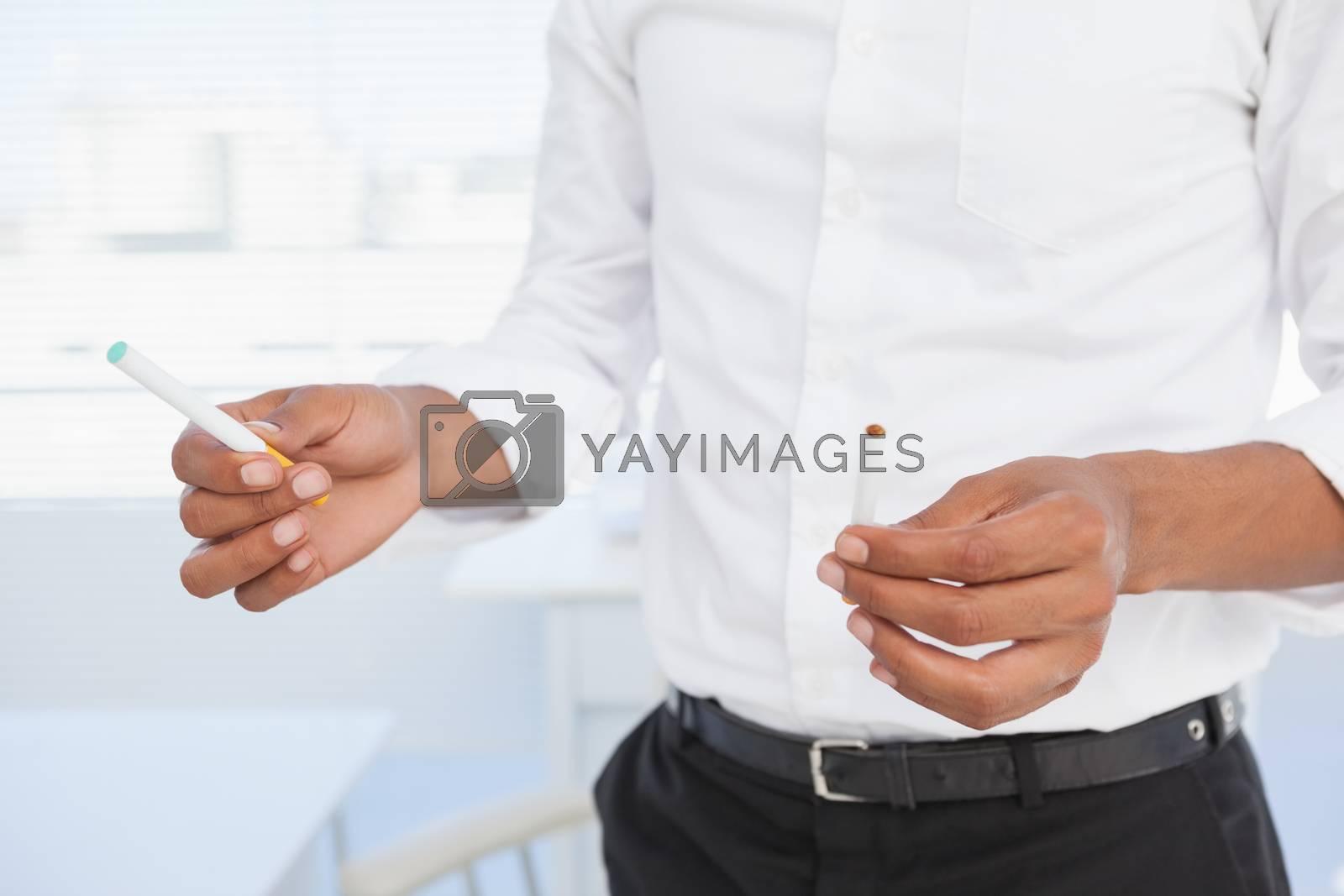 Royalty free image of Businessman deciding between electronic or normal cigarette by Wavebreakmedia