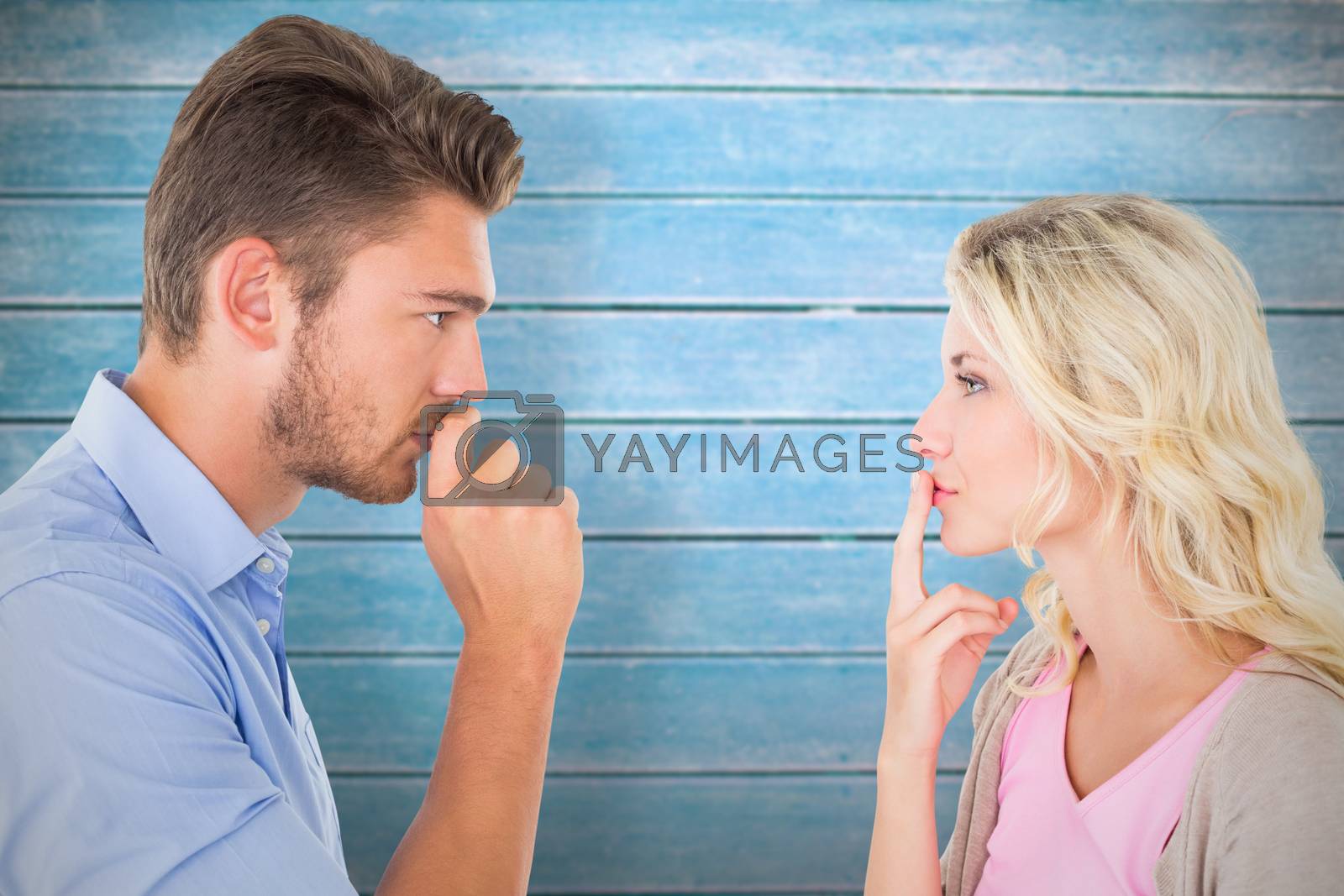 Royalty free image of Composite image of young couple staying silent with fingers on lips by Wavebreakmedia