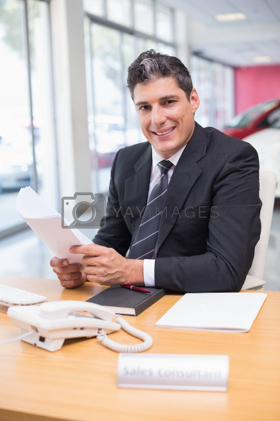 Royalty free image of Smiling salesperson holding a document by Wavebreakmedia