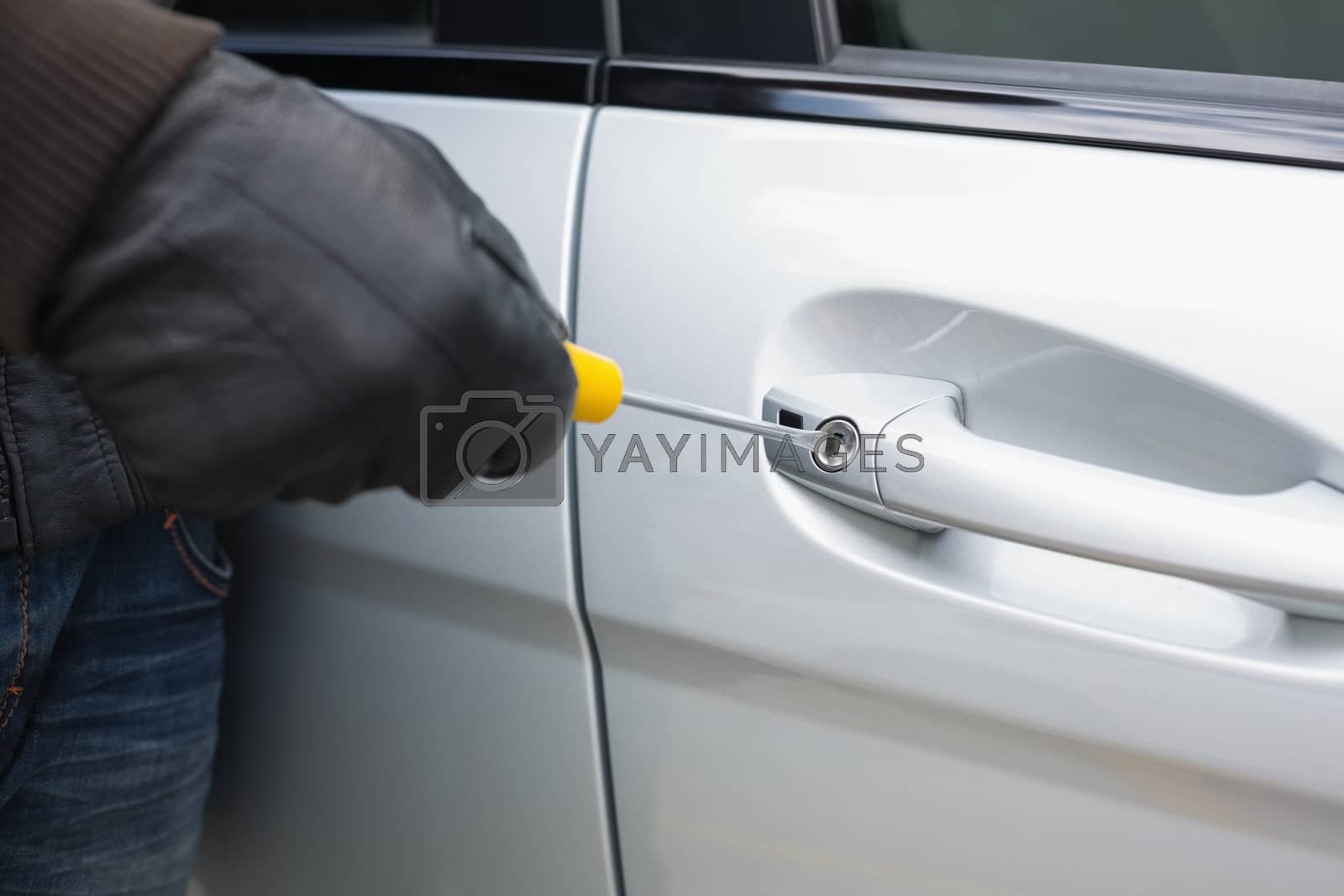 Royalty free image of Thief breaking into car with screwdriver by Wavebreakmedia