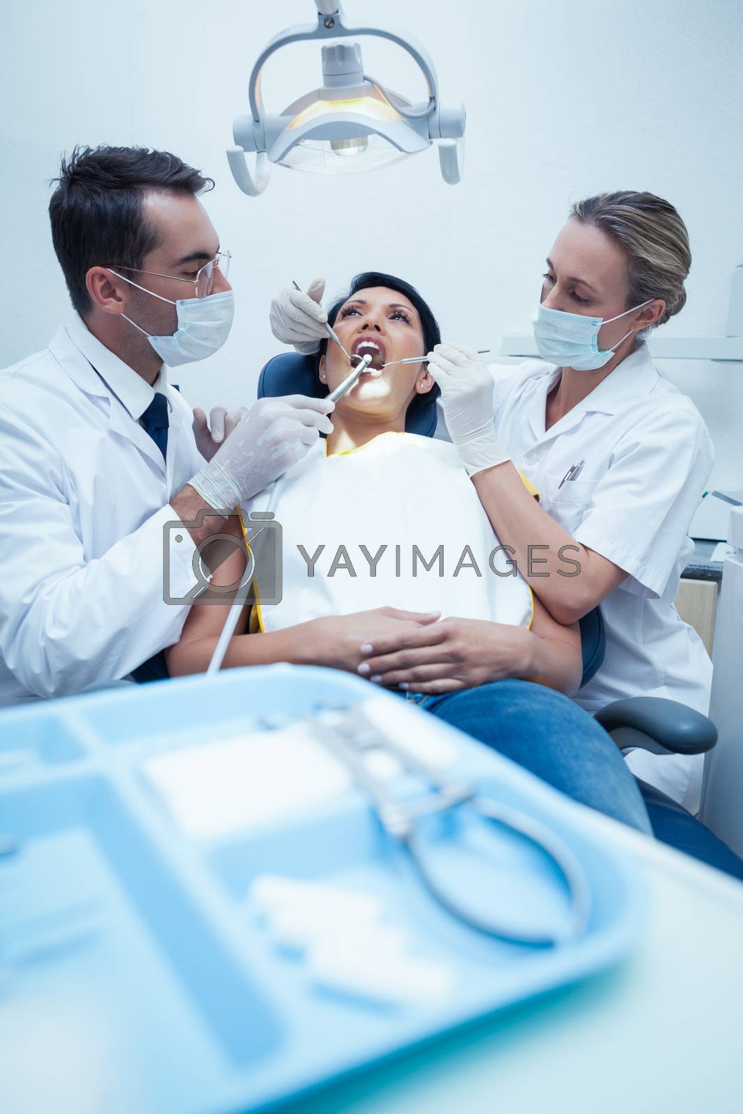 Royalty free image of Dentist with assistant examining womans teeth by Wavebreakmedia