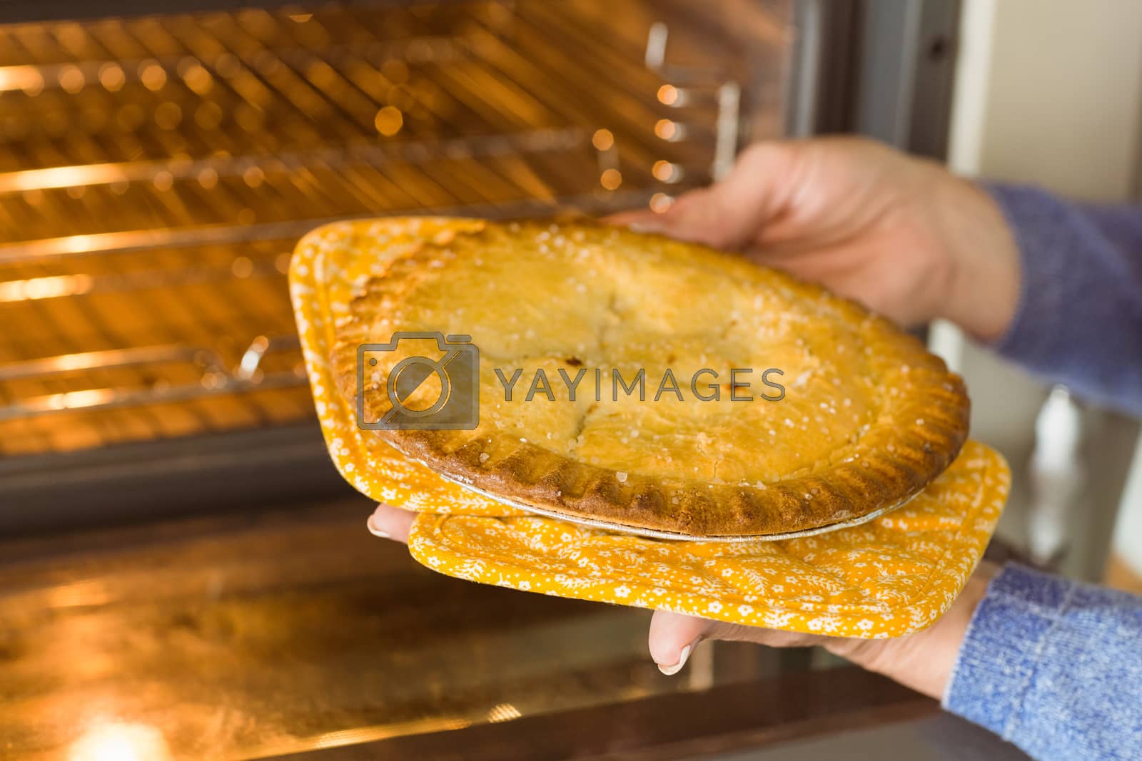 Royalty free image of Woman taking fresh pie out of oven by Wavebreakmedia