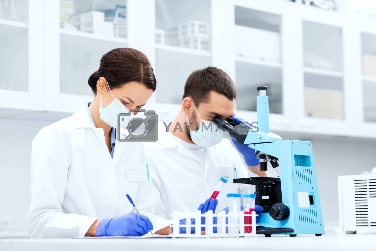 Royalty free image of scientists with clipboard and microscope in lab by dolgachov