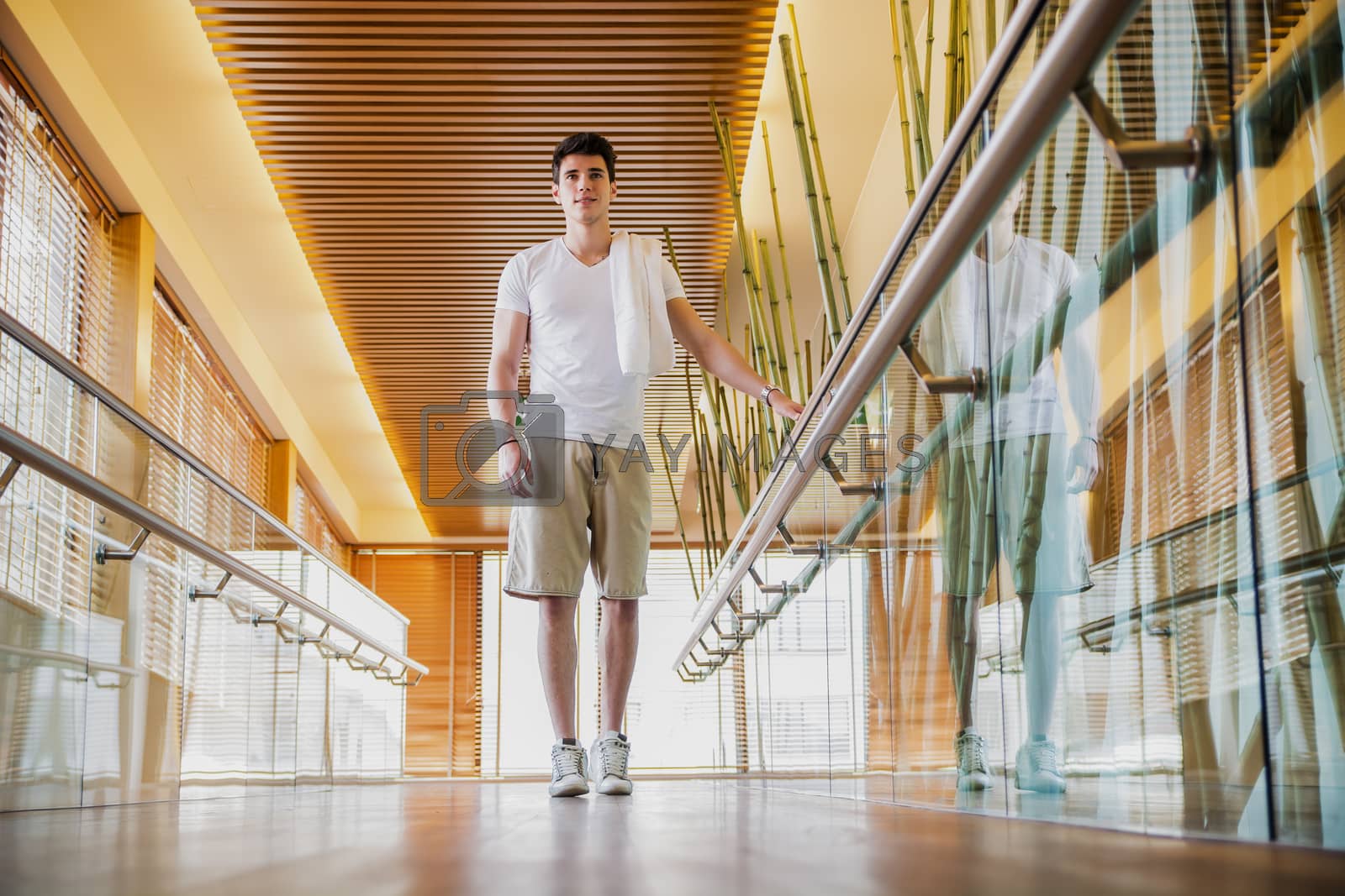 Royalty free image of Young Man Standing in Hallway Holding Hand Rail by artofphoto