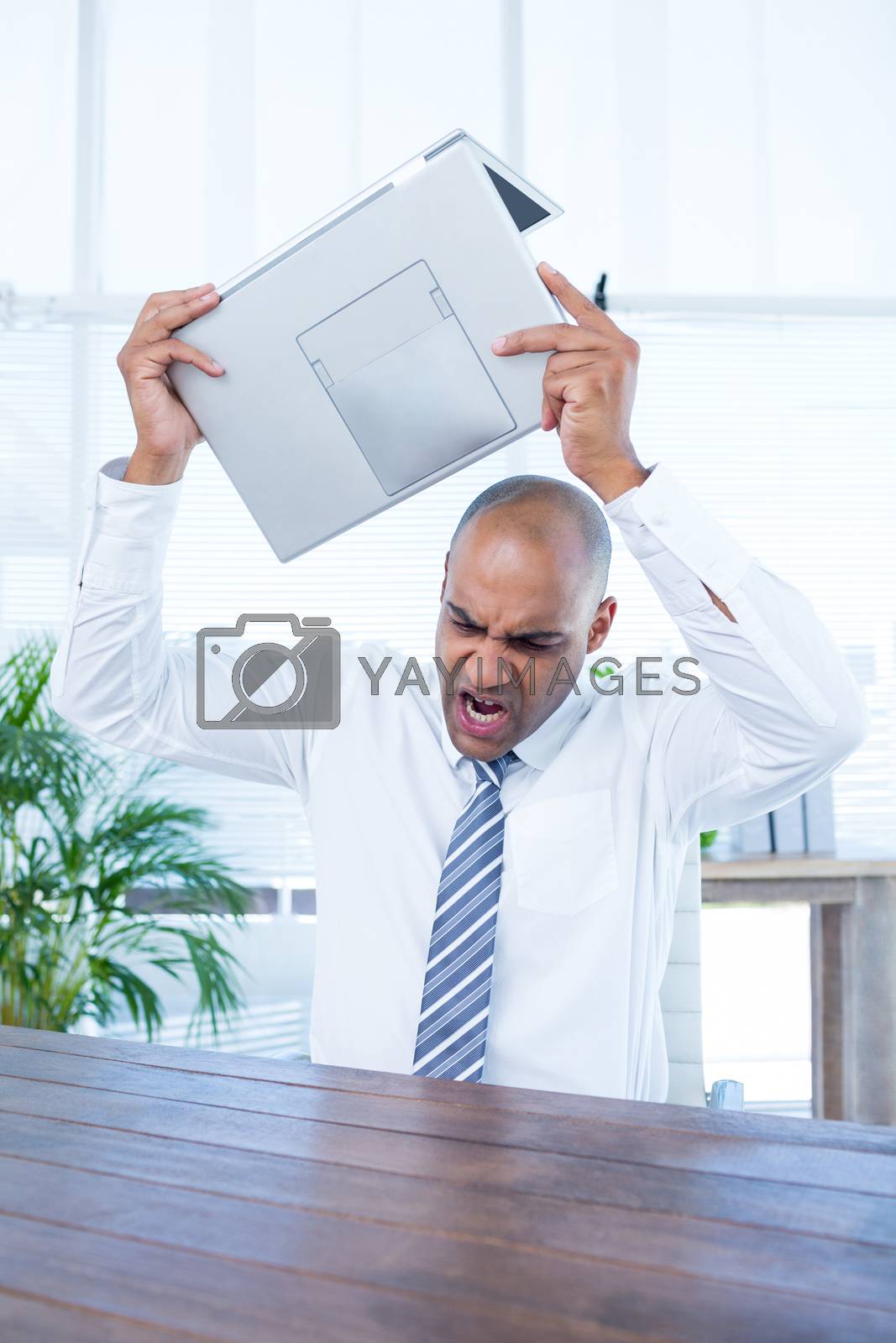 Royalty free image of Irritated businessman about to break his laptop by Wavebreakmedia