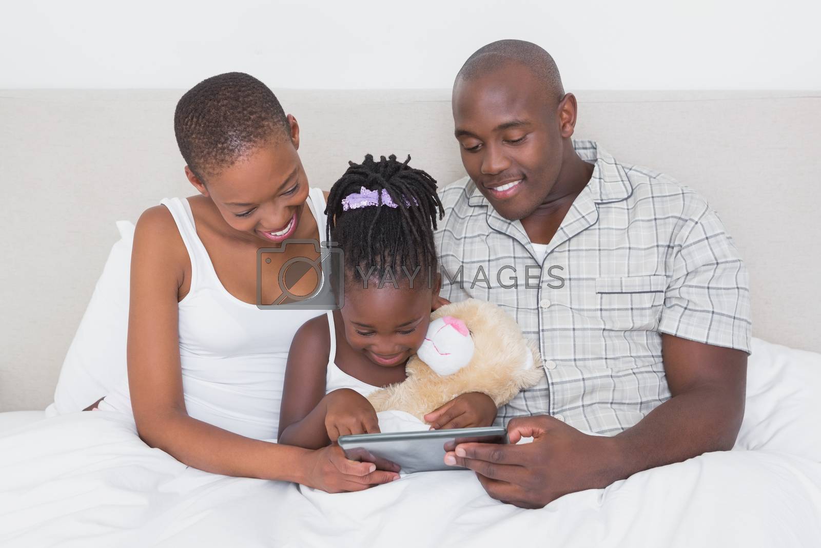 Royalty free image of Pretty couple using tablet with their daughter in bed  by Wavebreakmedia