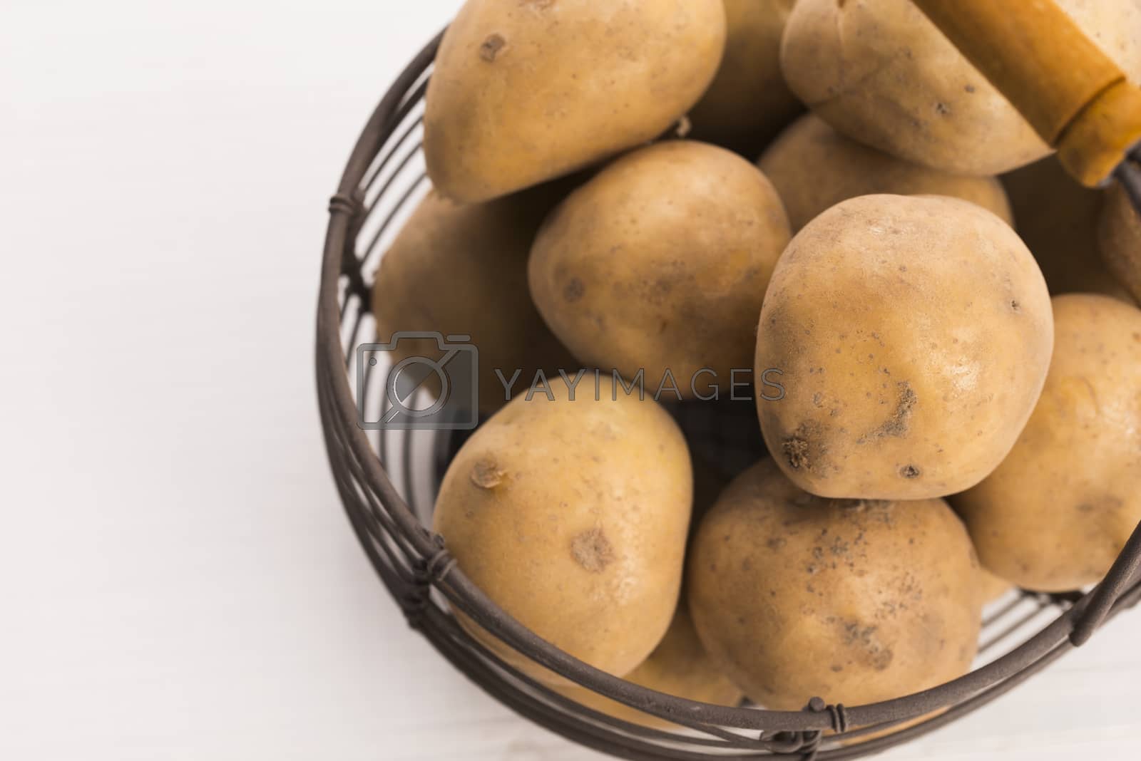 Royalty free image of uncooked potatoes in wire basket by joannawnuk