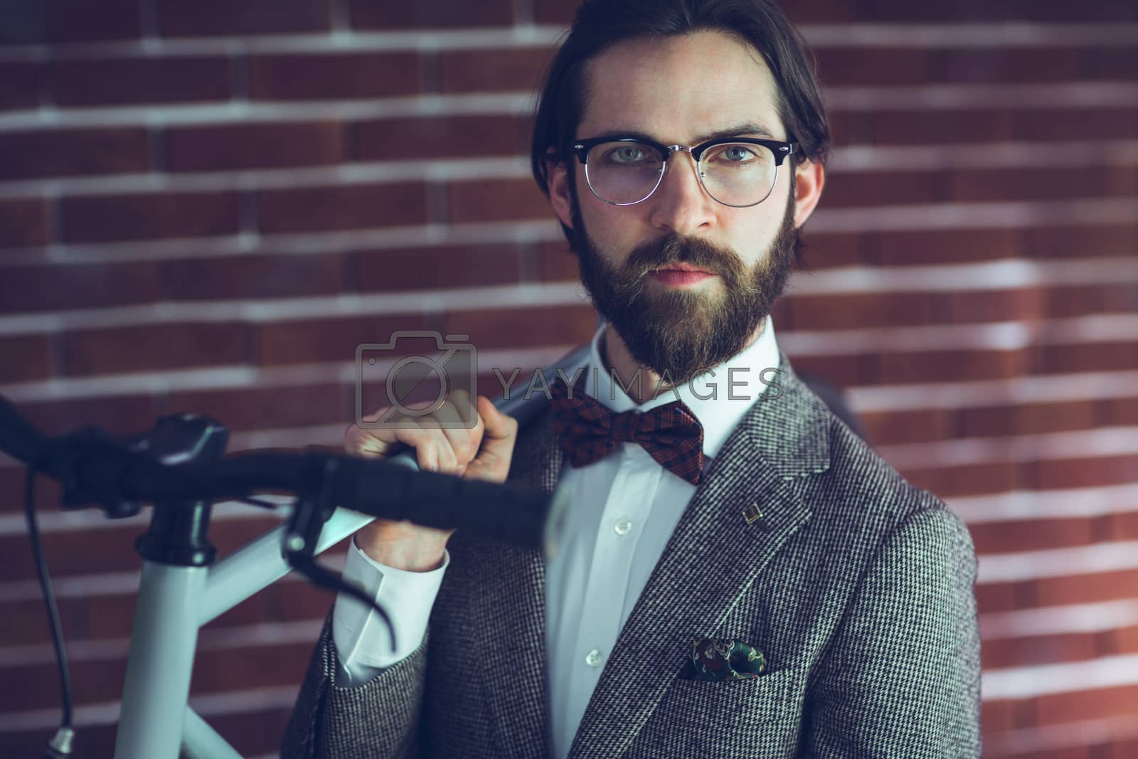 Royalty free image of Portrait of confident hipster carrying bicycle by Wavebreakmedia