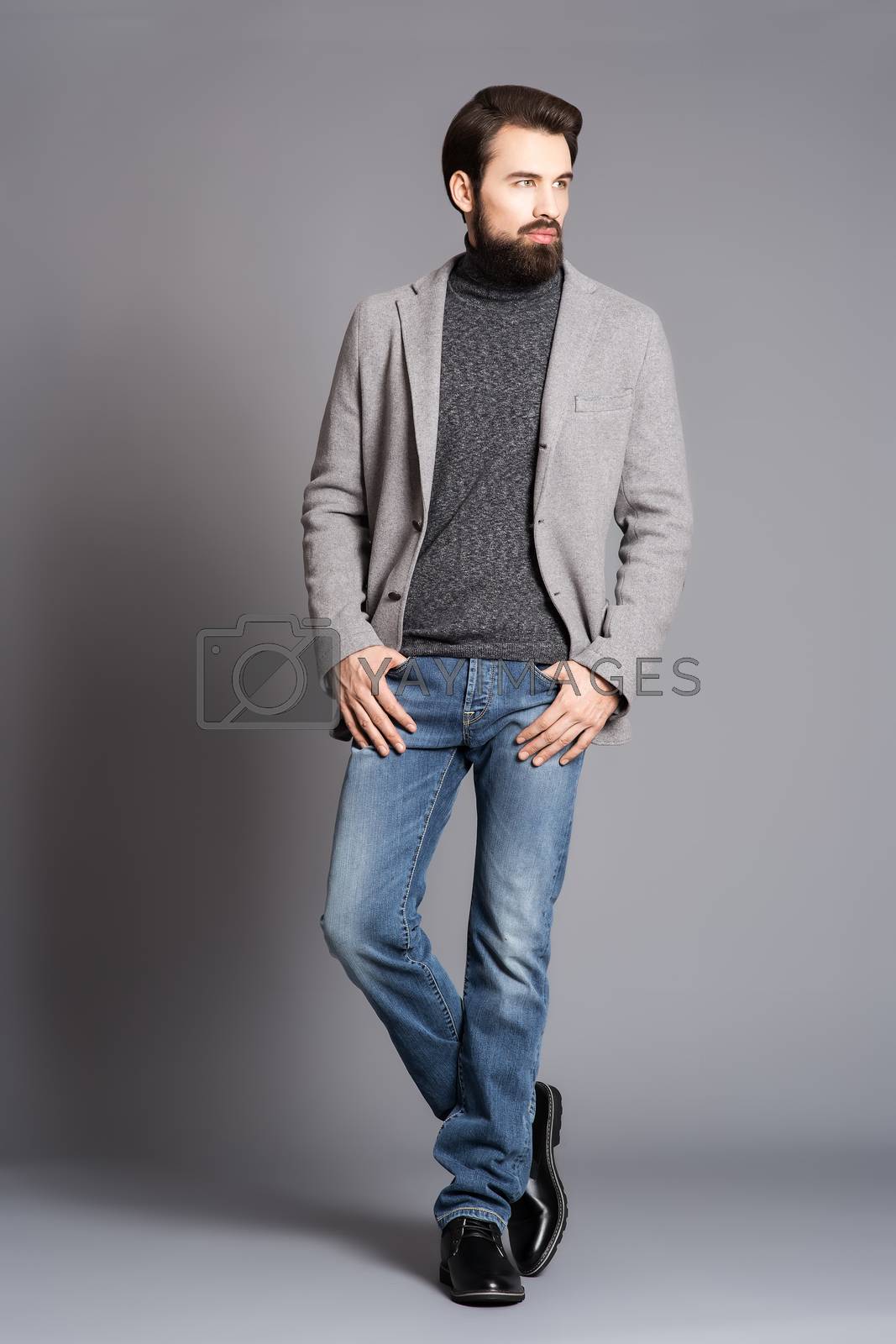 Royalty free image of a young man with a beard, wearing a jacket and jeans standing in by timofeev