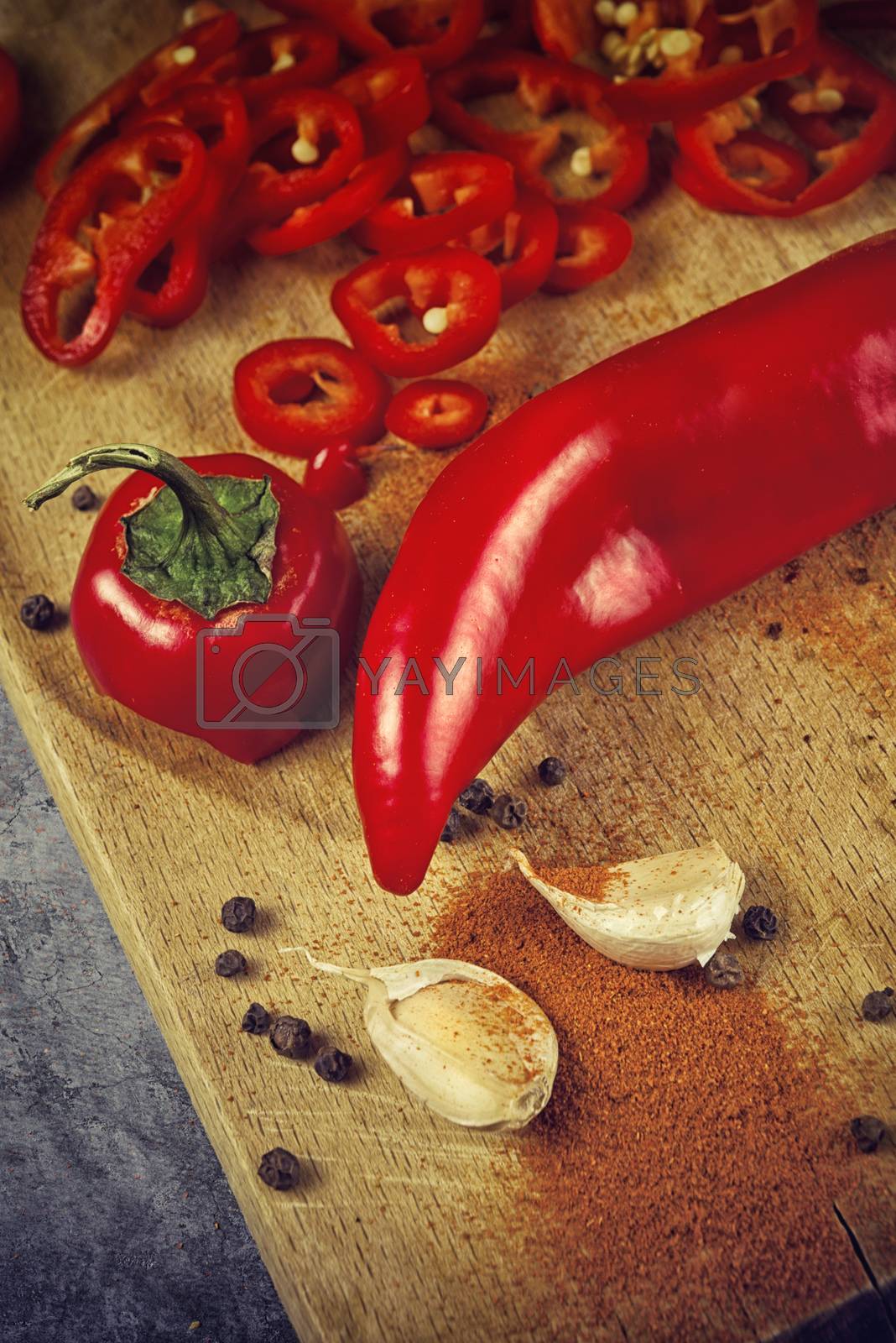 Red Hot Chili Pepper, Spice and Organic Garlic on Wooden Kitchen Plate as Hot Food Ingredients for Spicy Piquant Cuisine. Selective focus with shallow depthof field.