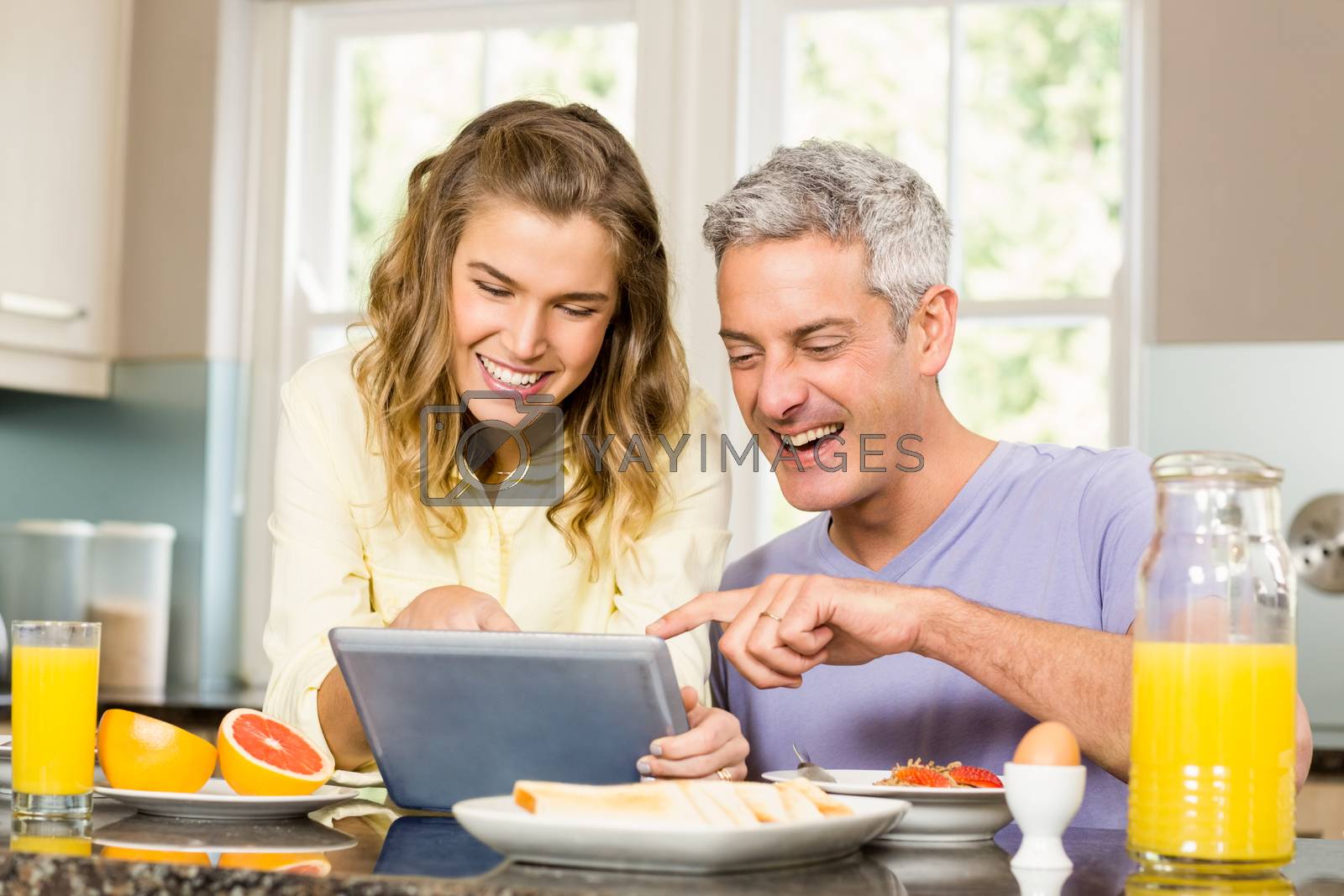 Royalty free image of Happy couple using tablet and having breakfast by Wavebreakmedia