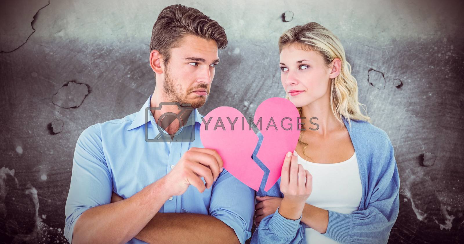 Royalty free image of Composite image of couple holding two halves of broken heart by Wavebreakmedia