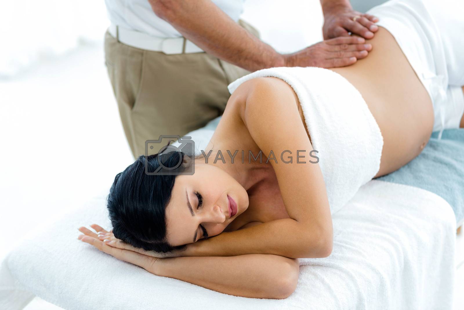 Royalty free image of Pregnant woman receiving a back massage from masseur by Wavebreakmedia