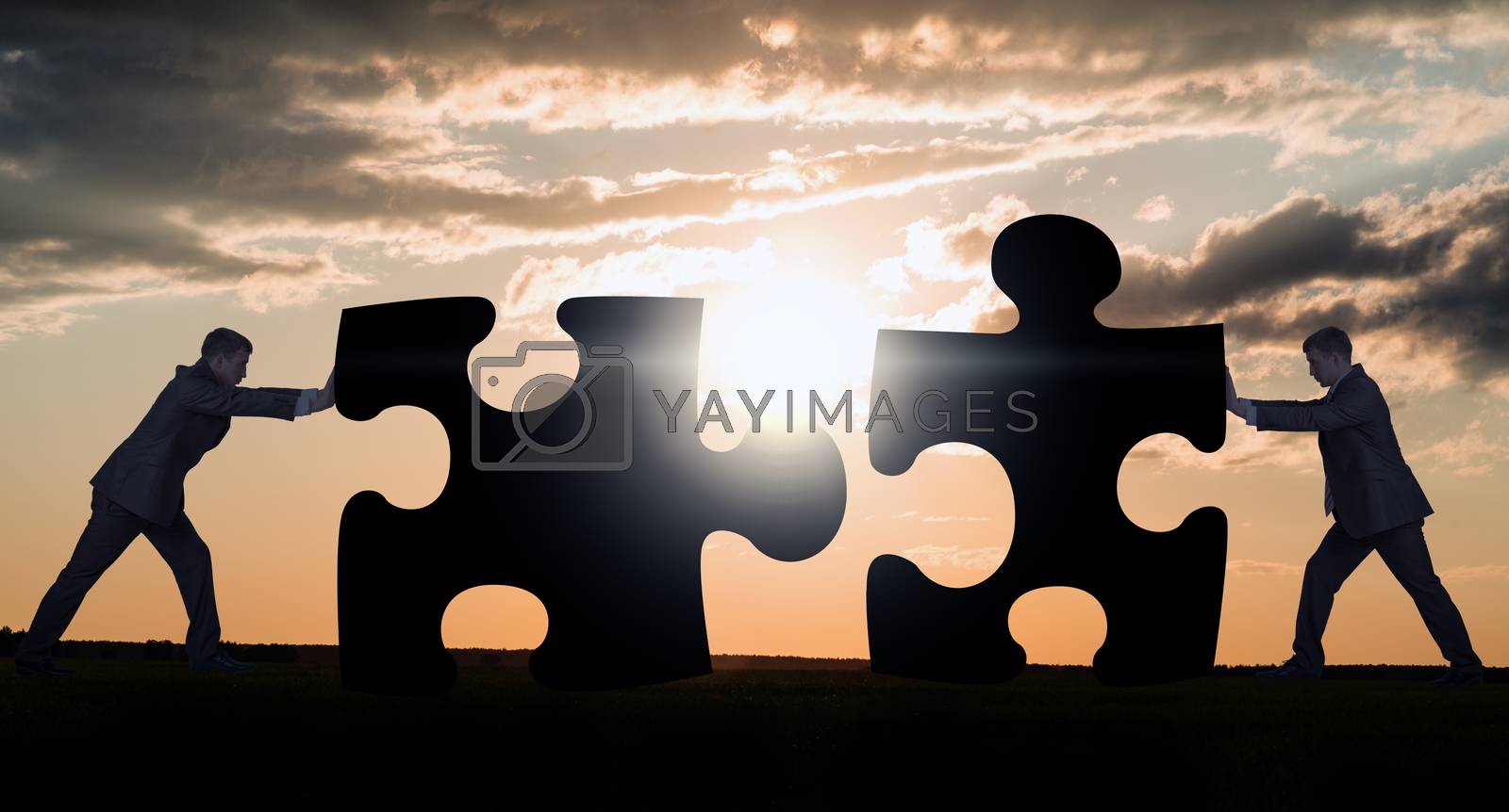 Royalty free image of Two businessmen combining pieces of puzzle by cherezoff