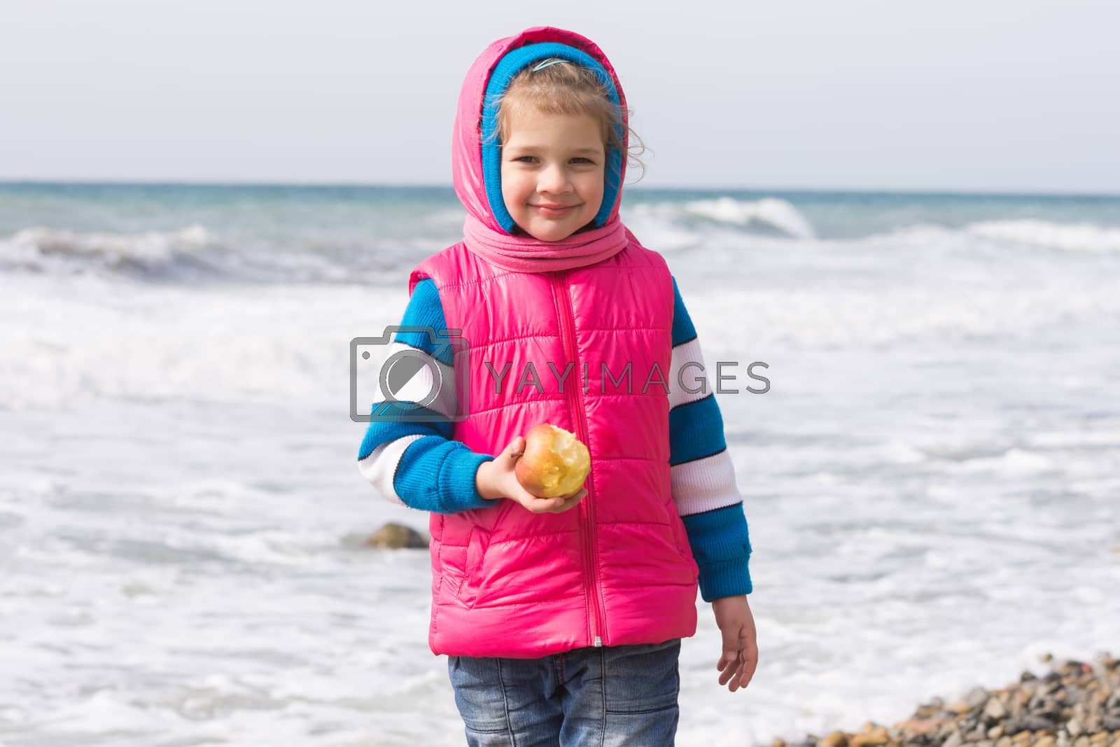 Royalty free image of Portrait of a five year old girl with an apple on the beach by Madhourse