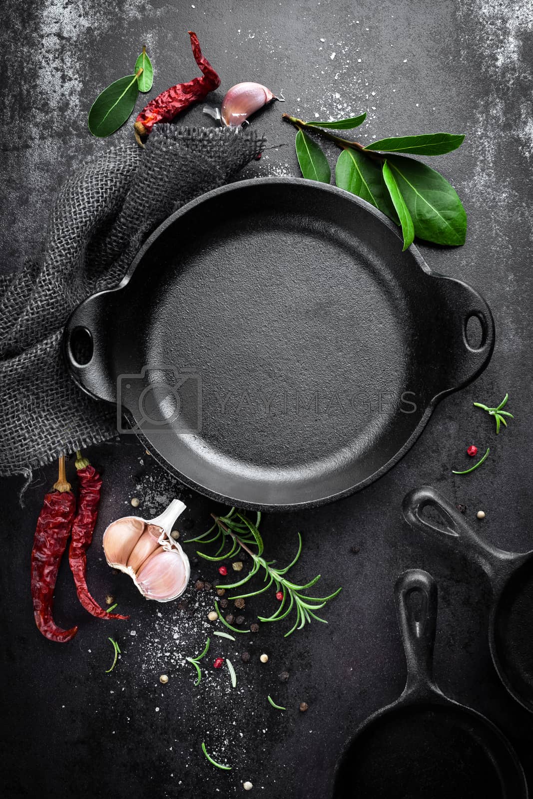 Royalty free image of cast iron pan and spices on black metal culinary background, view from above by yelenayemchuk