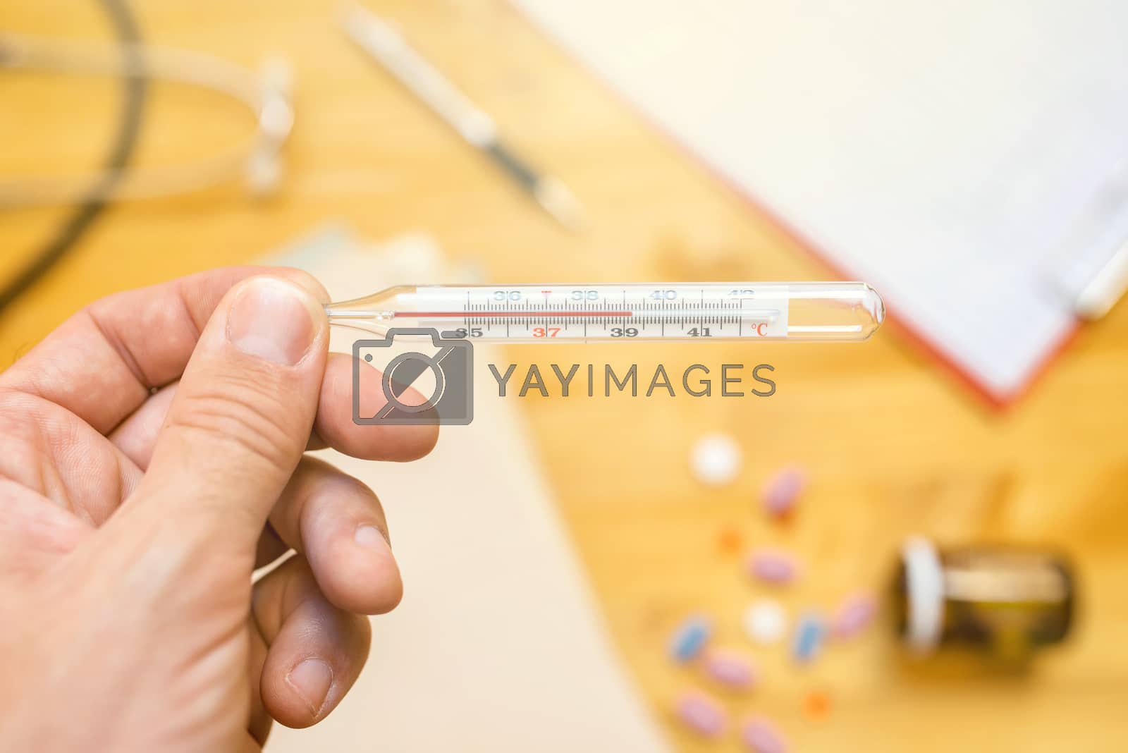 Royalty free image of Hand with medical thermometer measuring human body temperature by stevanovicigor
