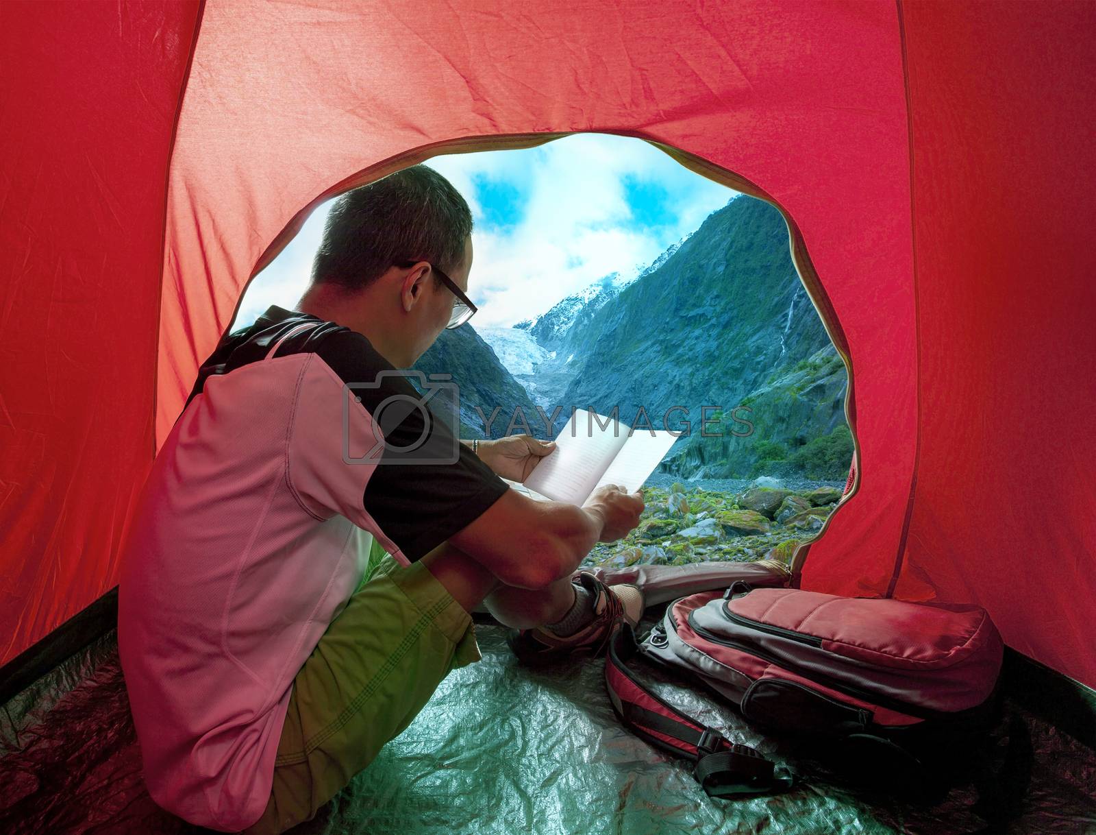 Royalty free image of camping man reading a traveling guild book in camp tent beautifu by khunaspix