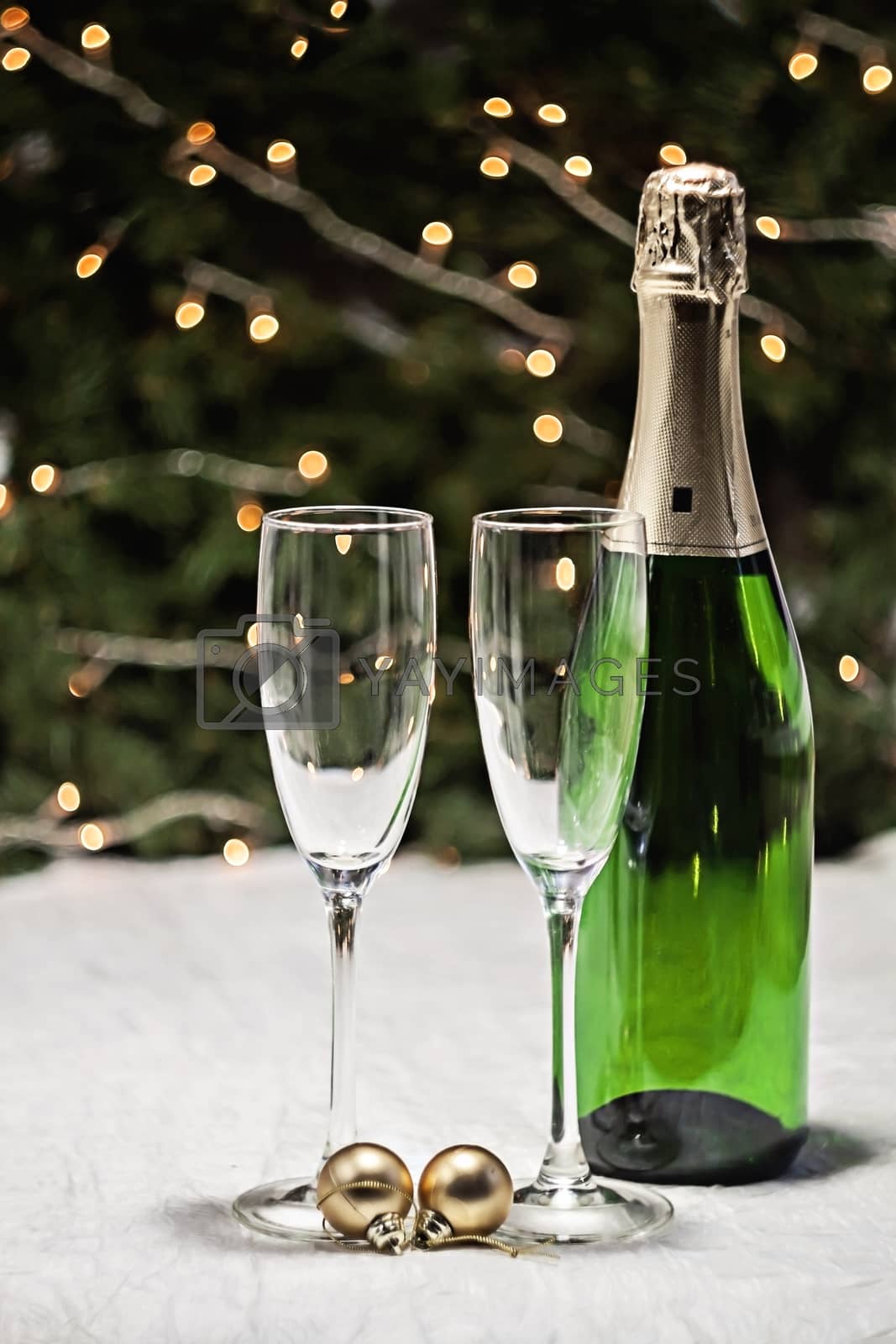 Royalty free image of two glasses and a bottle of champagne is on a festive tablecloth by Tanacha