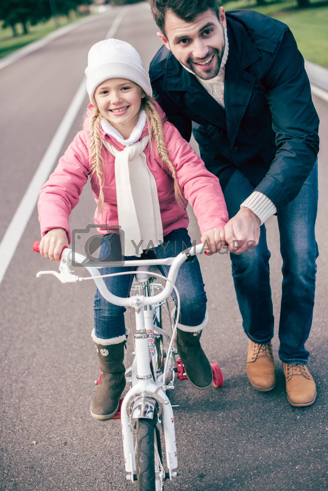 Royalty free image of Father teaching daughter to ride bicycle by LightFieldStudios