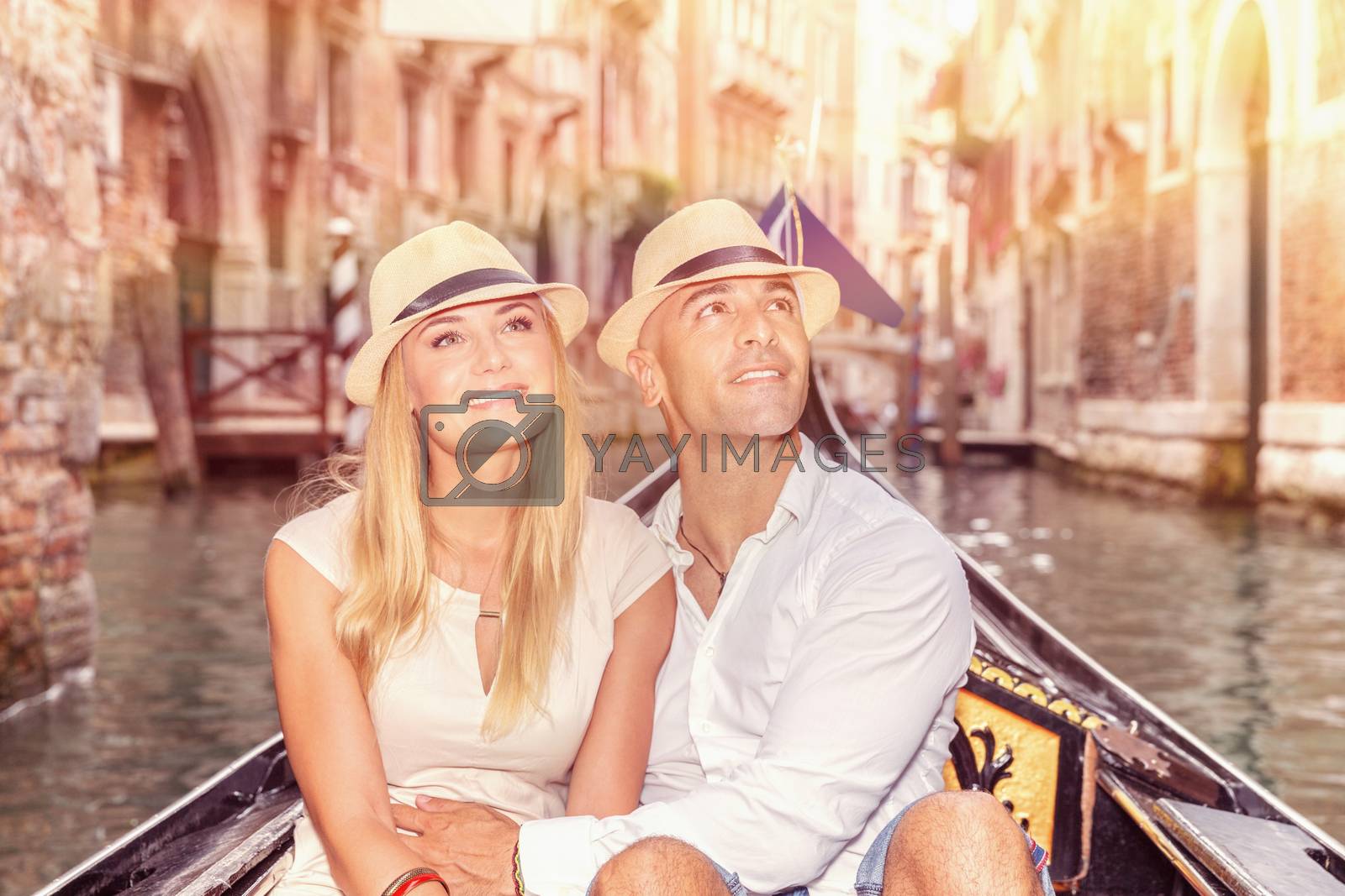 Portrait of a nice couple sitting in the gondola and enjoying wonderful trip along canal on narrow Venice street, romantic travel to Italy, Europe