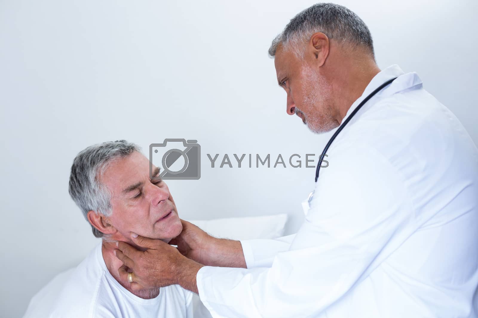 Royalty free image of Male doctor examining senior mans neck by Wavebreakmedia