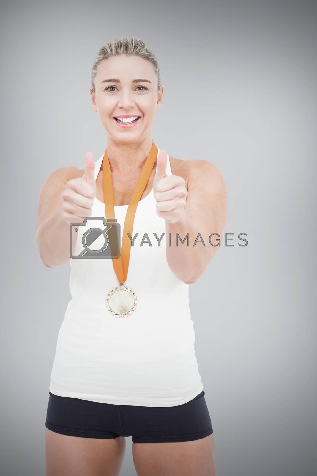Royalty free image of Composite image of female athlete wearing a medal and showing thumbs up by Wavebreakmedia