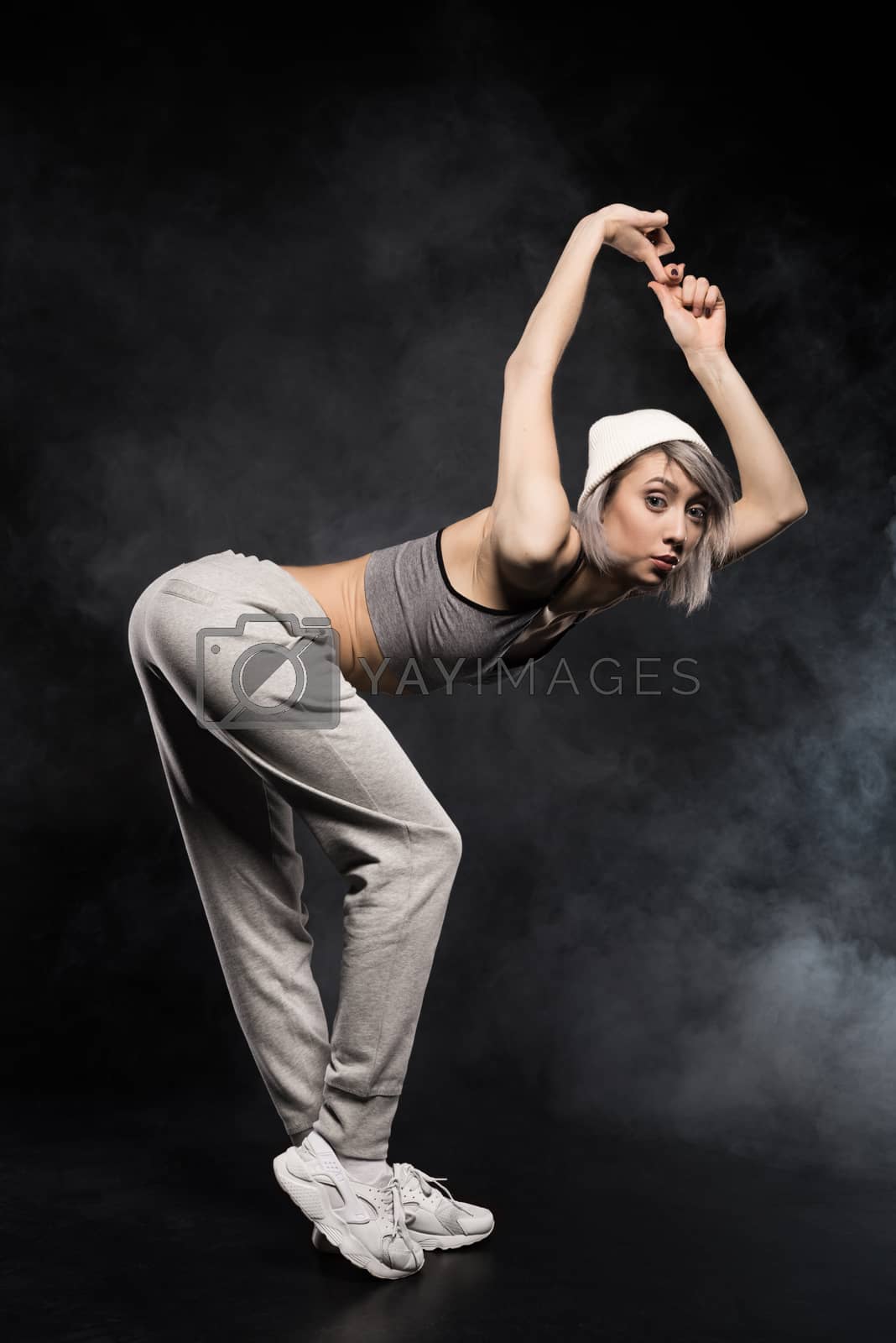 Royalty free image of side view of woman in sports clothing dancing on black by LightFieldStudios