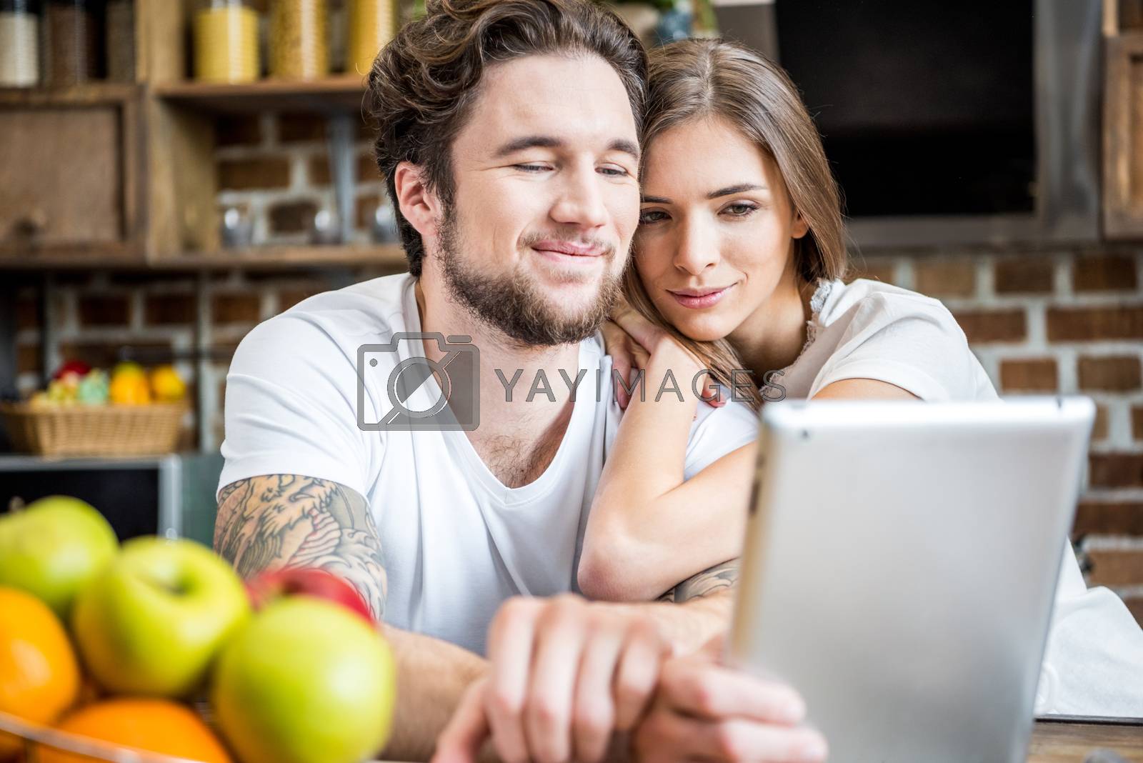 Royalty free image of Couple using digital tablet at kitchen    by LightFieldStudios