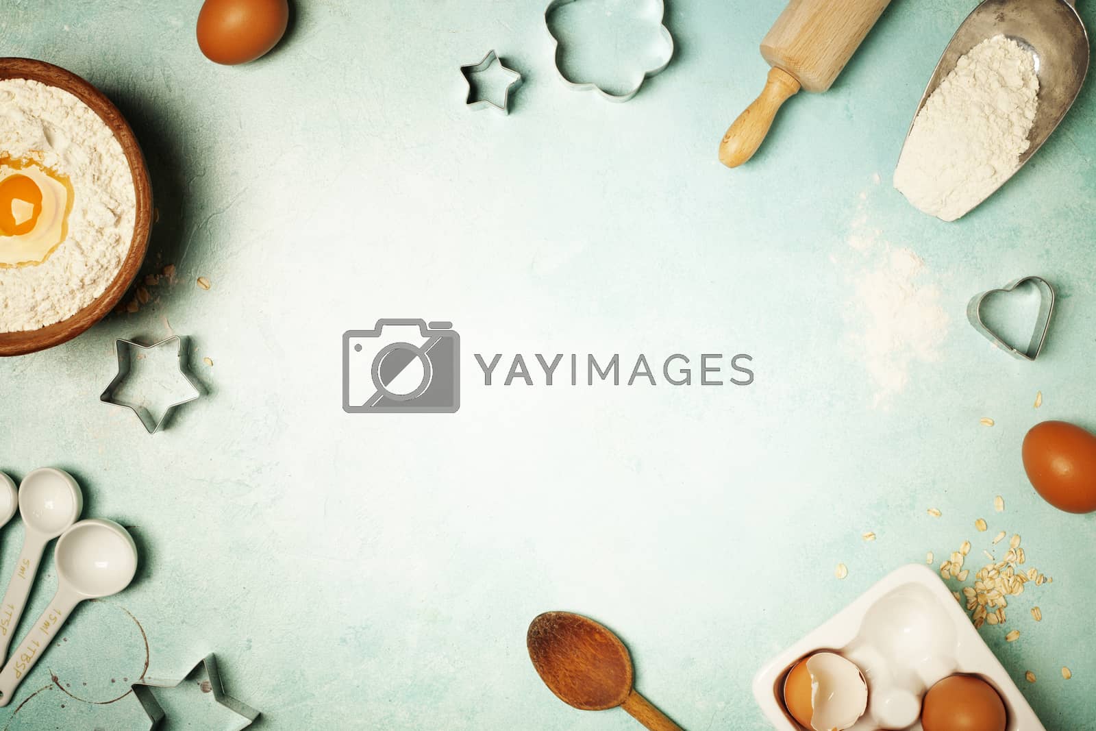 Baking background with flour, eggs and kitchen tools on blue rustic table. Top view. Flat lay style.
