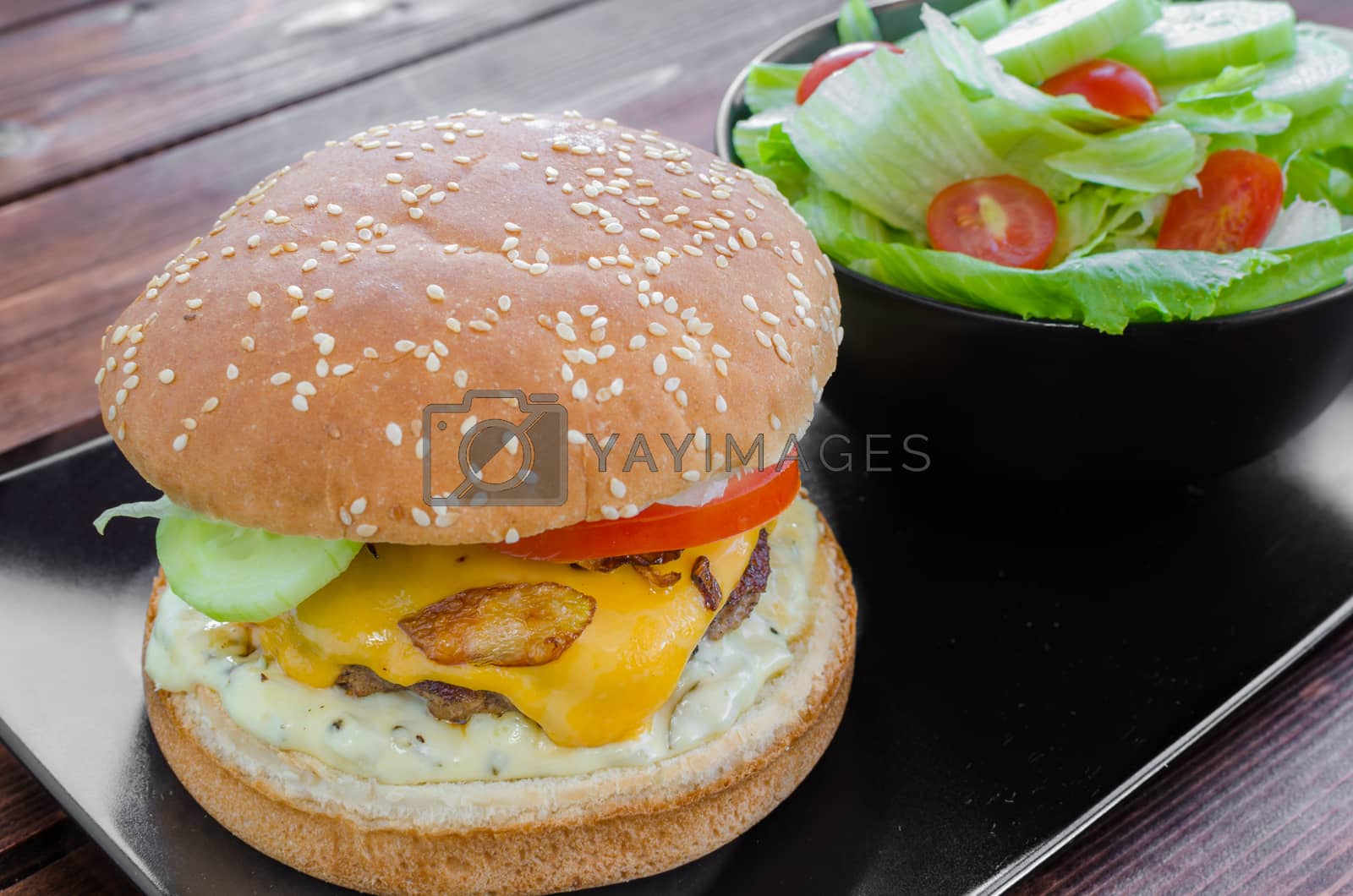 Royalty free image of Cheeseburger with bacon and tartar sauce and garden salad by Peteer