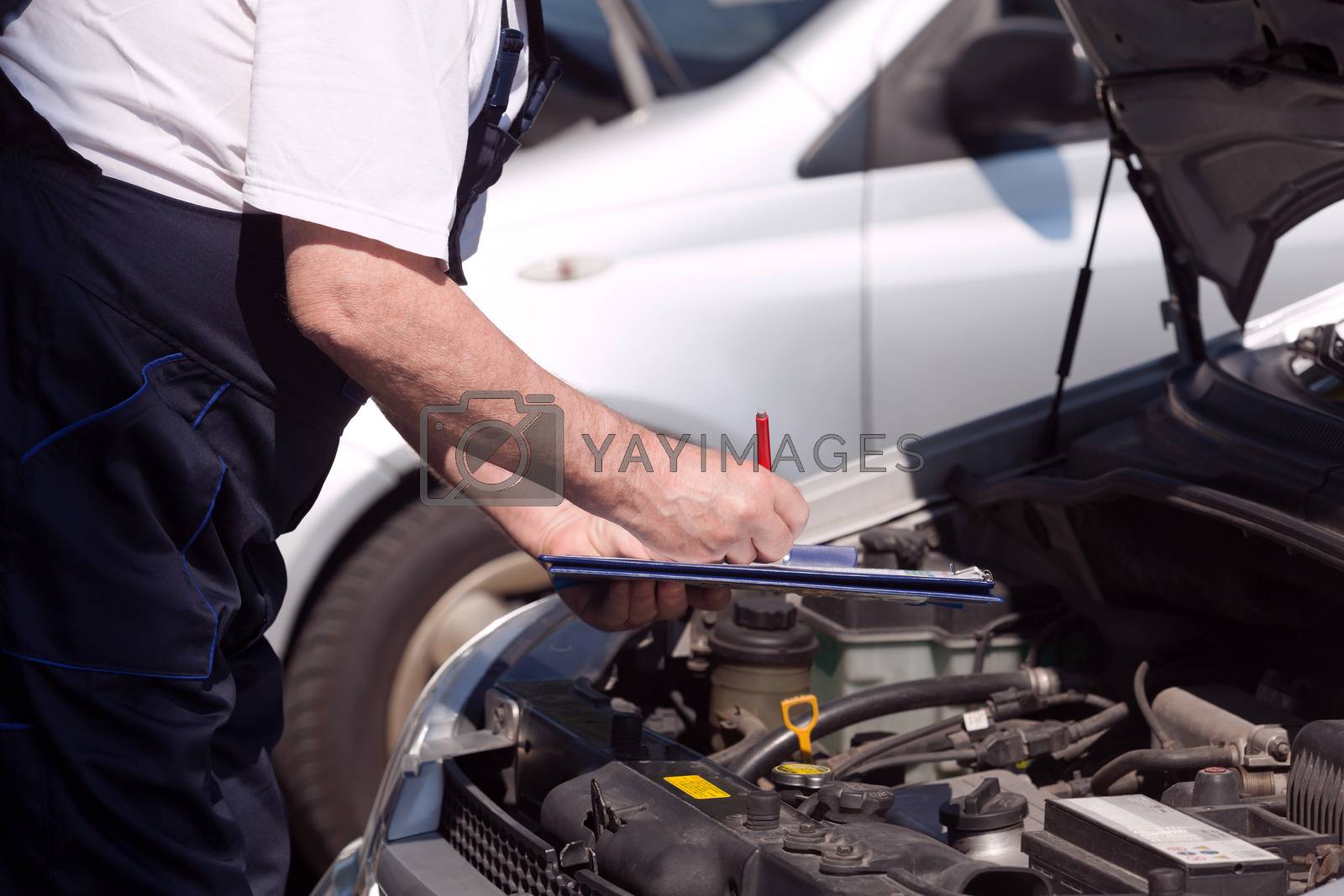 Royalty free image of Car or motor mechanic checking a car engine and writing on the c by wellphoto