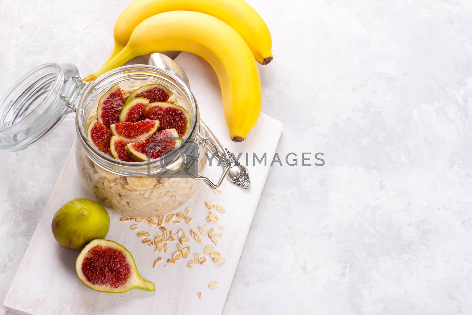 Old fashion oats with greek yogurt , banana and figs in a jar on white rustic background