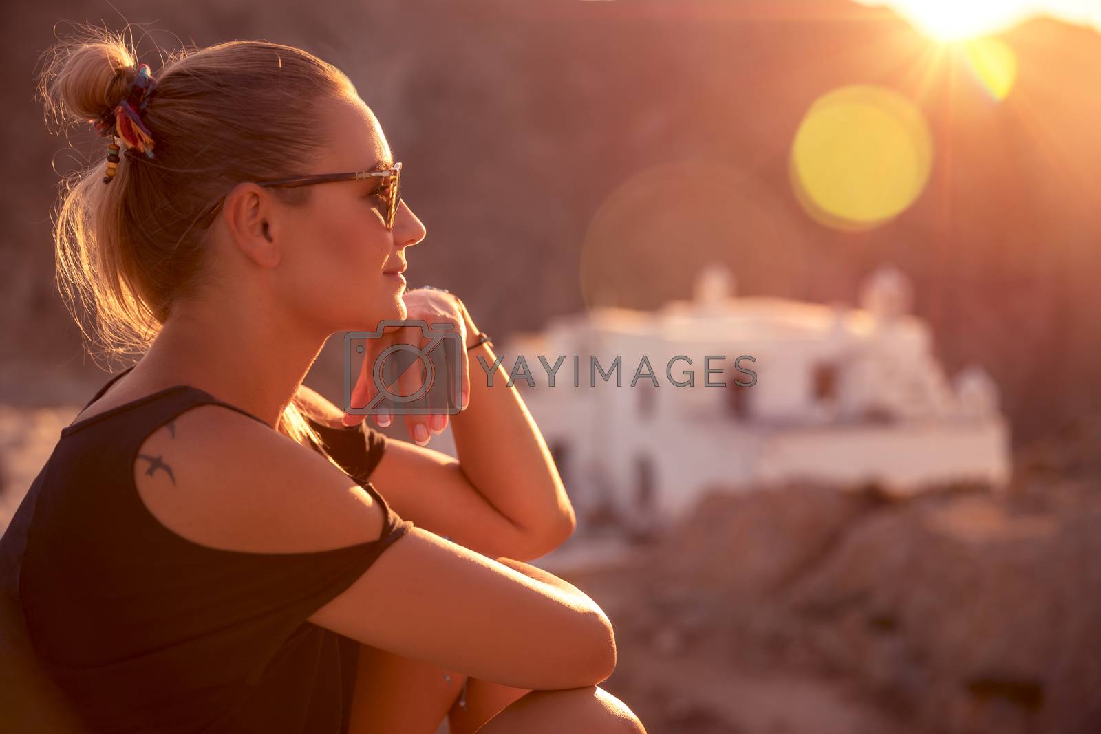 Beautiful woman enjoying spiritual travel to the wonderful place, sunset light scene, sitting on the mountains near the monastery, happy summer holidays