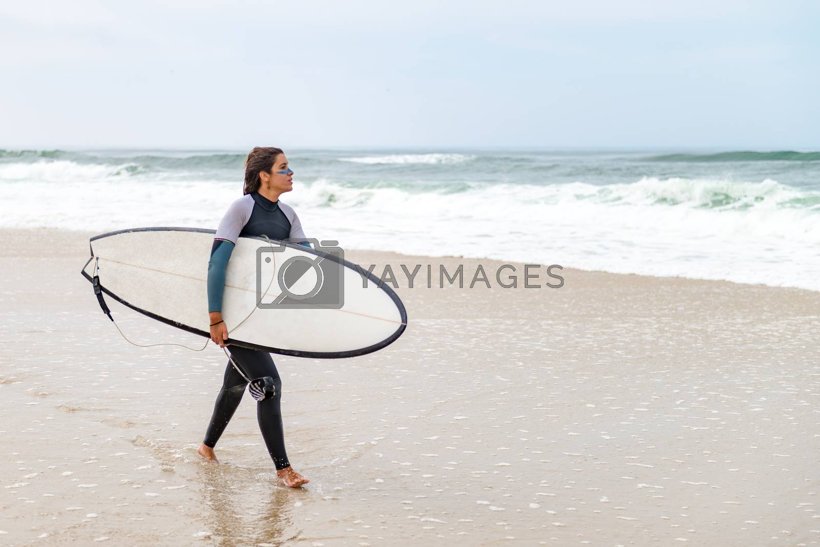 Royalty free image of Young female surfer wearing wetsuit by homydesign