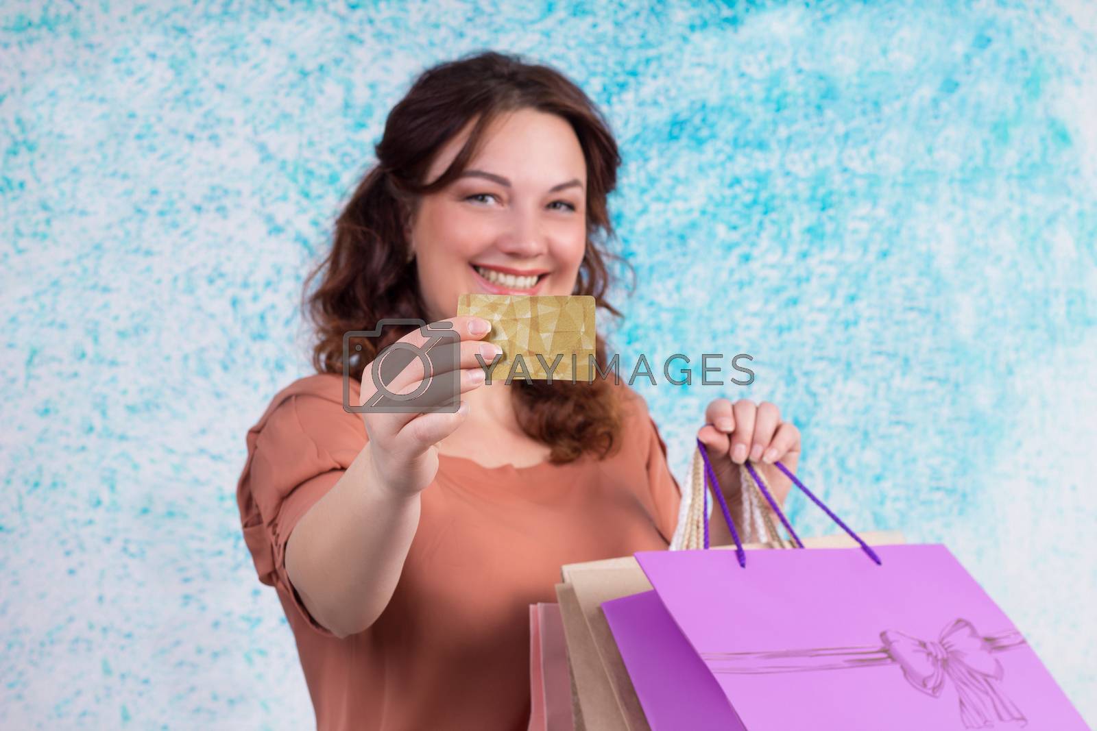 Royalty free image of Smiling woman with colourful shopping paper bags shows credit ca by VeraVerano