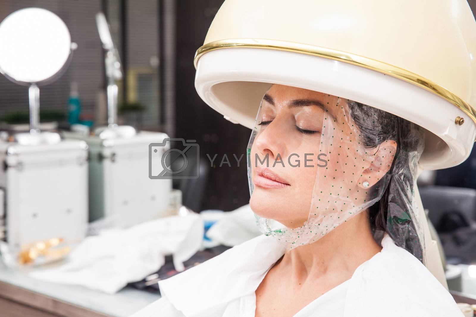Royalty free image of Woman under a professional hair steamer with a hair treatment by anamejia18