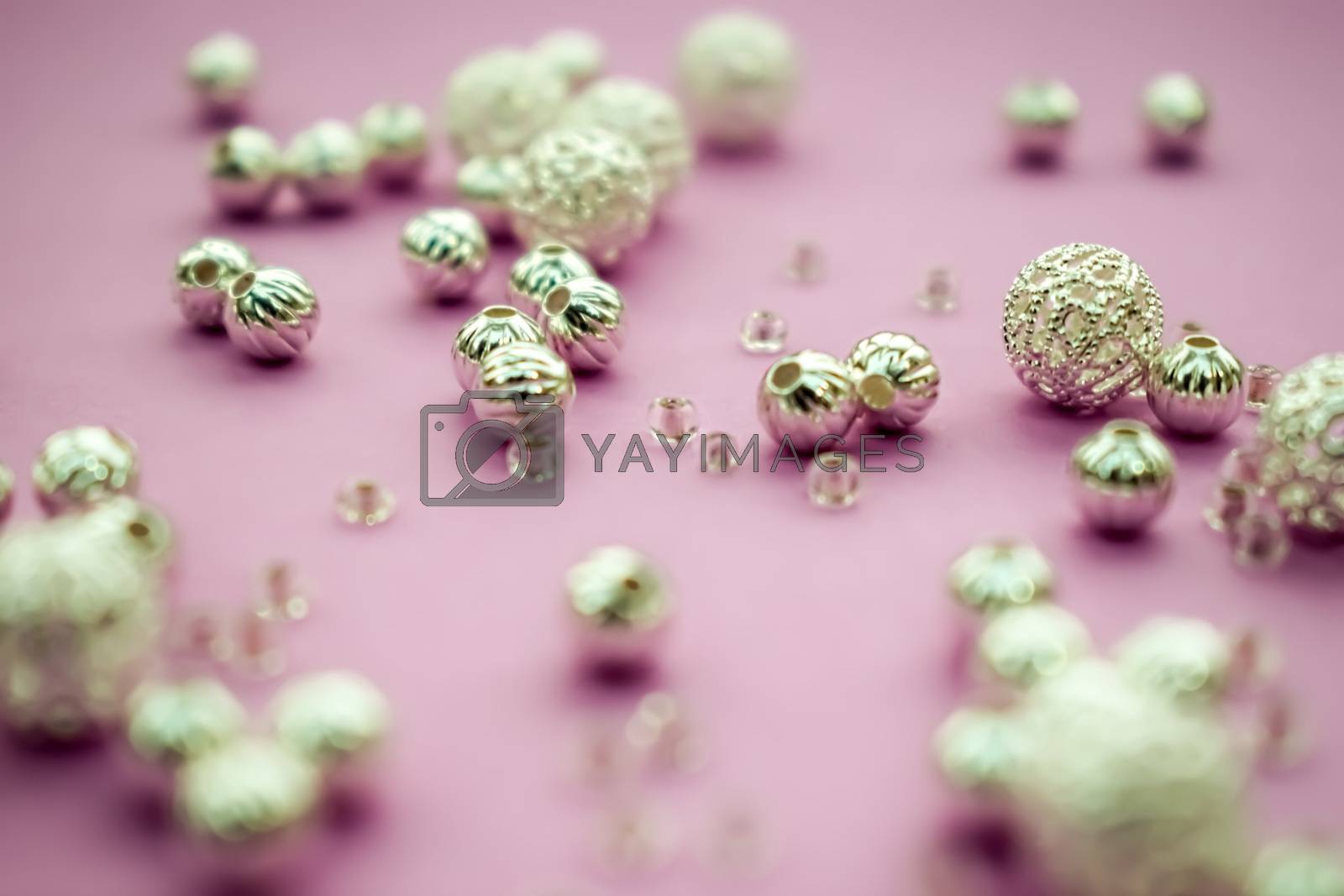 Royalty free image of selection of scattered silver beads on pink background by sarahdavies576@gmail.com