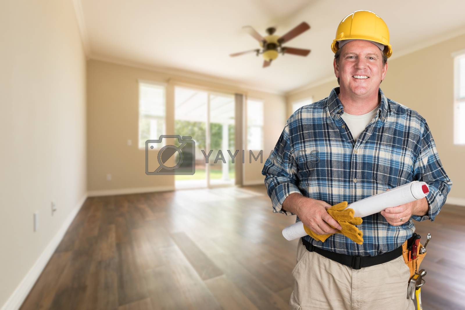 Royalty free image of Contractor With Plans and Hard Hat Inside Empty Room with Wood Floors. by Feverpitched
